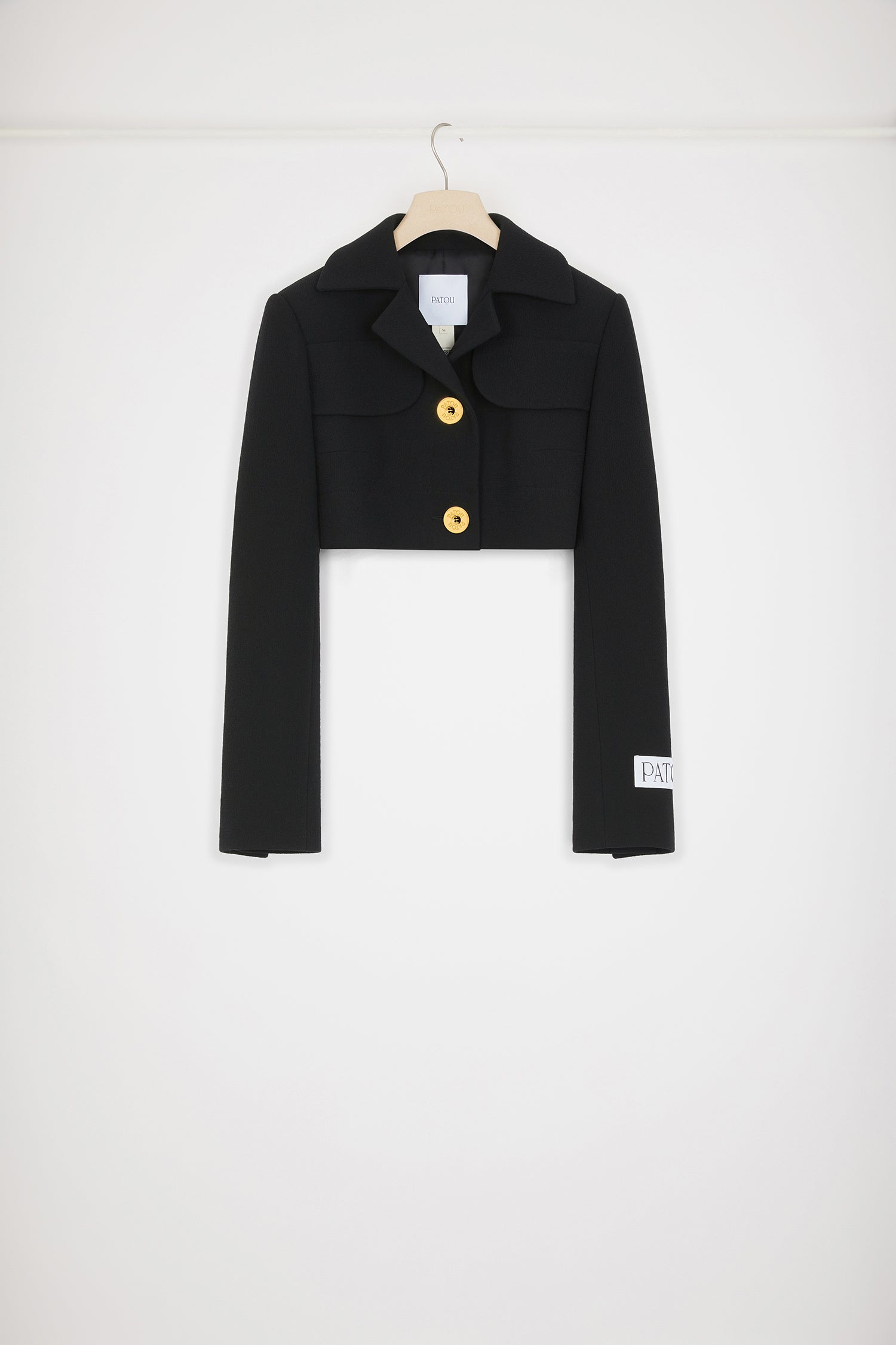 Patou - Giacca cropped in crepe di lana - Black - Il tailoring contemporaneo in versione corta.Giacca in doppio crepe di lana nero. Modello corto. Rever classico. Tasche con patta al petto. Bottoni oro incisi Patou. Polsini abbottonati. Etichetta Patou sulla manica sinistra. Modello foderato.Questo modello è cropped.