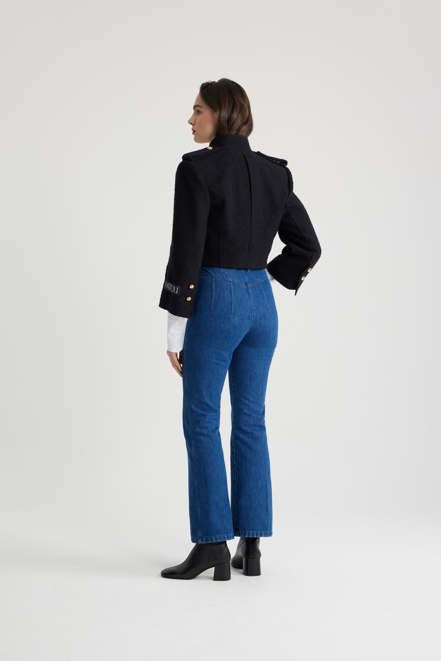 Patou - サステナブルウール&オーガニックコットンツイード クロップド セーラージャケット - Black - ブラックのサステナブル ウール&オーガニックコットン製ツイード ジャケット。クロップド丈。ワイドカラー。ゴールドトーンの半球型JPボタン。ボタン付きショルダータブ。ウェルトポケット付き。ややクロップドスリーブ。袖口にボタン付き。左袖にパトゥラベル。裏地付き。フィット感のあるショートスタイル。