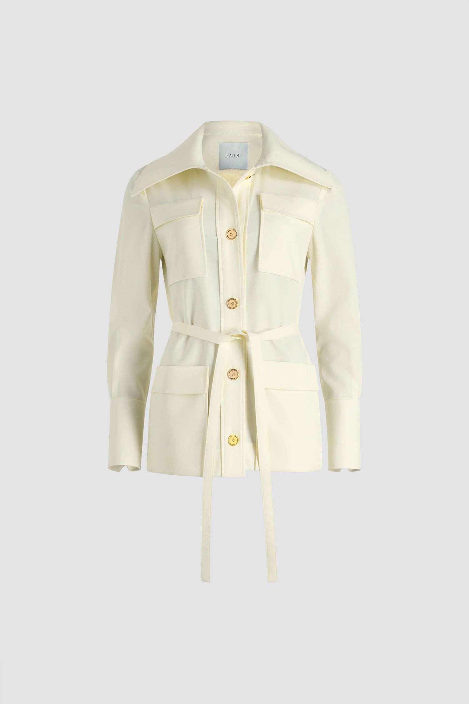 Patou - Safari jacket in sustainable technical wool twill - Ivory - Ivory sustainable technical wool twill jacket. Longline silhouette. Wide collar. Gold-tone JP monogram-engraved buttons. Multiple patch pockets at the front. Removable self-tie belt at the waist. Buttoned cuffs. Embroidered Patou logo on the left sleeve.