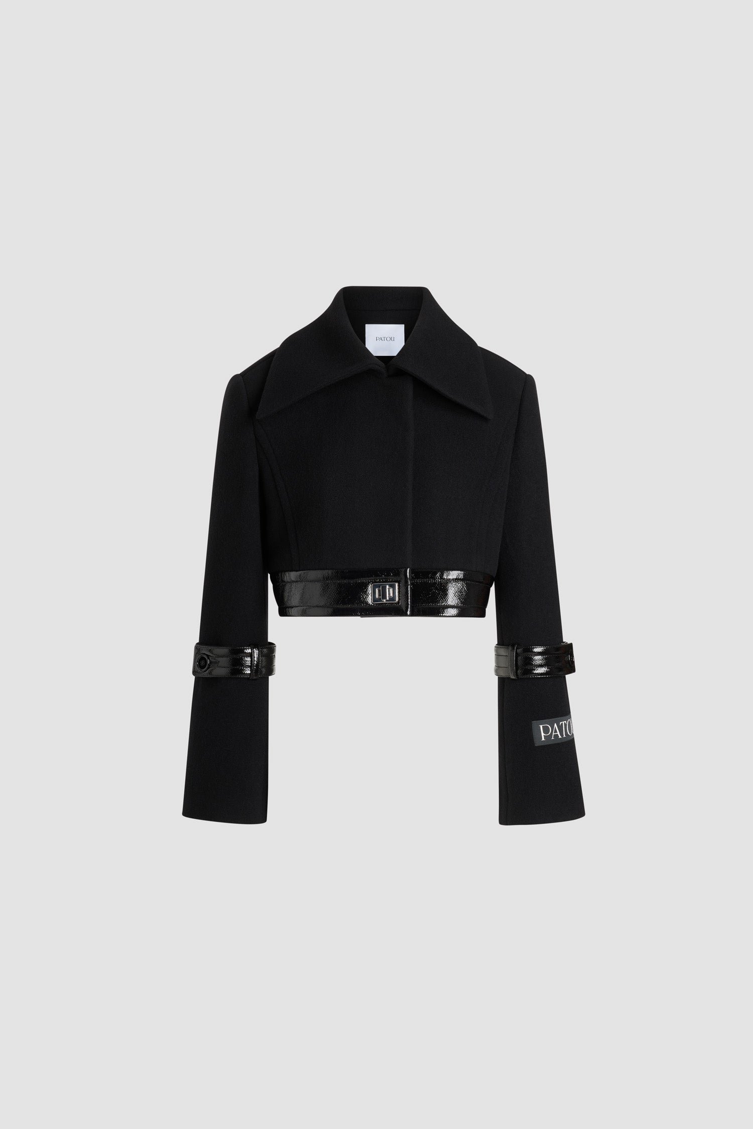 Patou - サステナブル ウールブレンド クロップド ロックジャケット - Black - ブラックのサステナブル ウール混紡ジャケット。丈の短いシルエット。シングルブレストスタイル。ワイドカラー。隠しボタン留め。シルバーカラーのロック留め付きのパテントレザー製ウエストバンド。袖にパテントレザー製のボタン付きタブ。左袖にPatouロゴラベル。裏地付き。