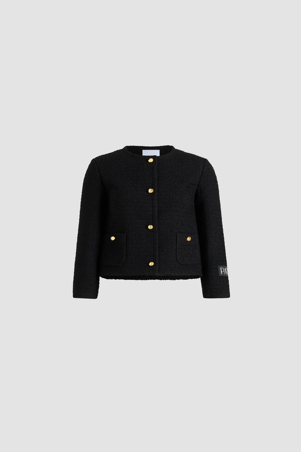 Patou - Veste courte sans col en tweed de laine mélangée éco-responsable - Black - Veste en tweed de laine mélangée éco-responsable noir. Modèle court. Construction à boutonnage simple. Modèle sans col. Boutonnage avant avec boutons boule dorés à monogramme JP. Poches plaquées boutonnées sur le devant. Étiquette Patou sur la manche gauche. Modèle doublé.