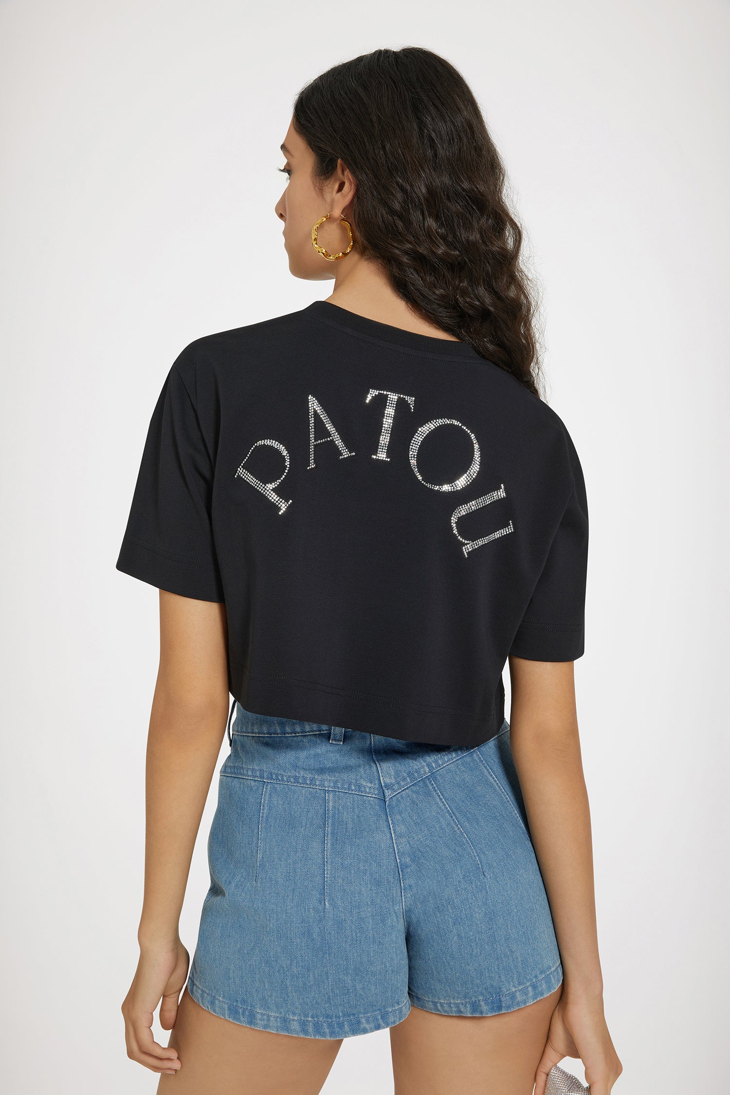 Patou - オーガニックコットン ディテール パトゥ クロップドTシャツ - Black - パトゥをまとって、煌びやかに、ハッピーに。ブラックのオーガニックコットン製Tシャツ。レギュラーフィット。クロップド丈。クルーネック。胸部分にクリスタルのJPモノグラム、背面にPatou。