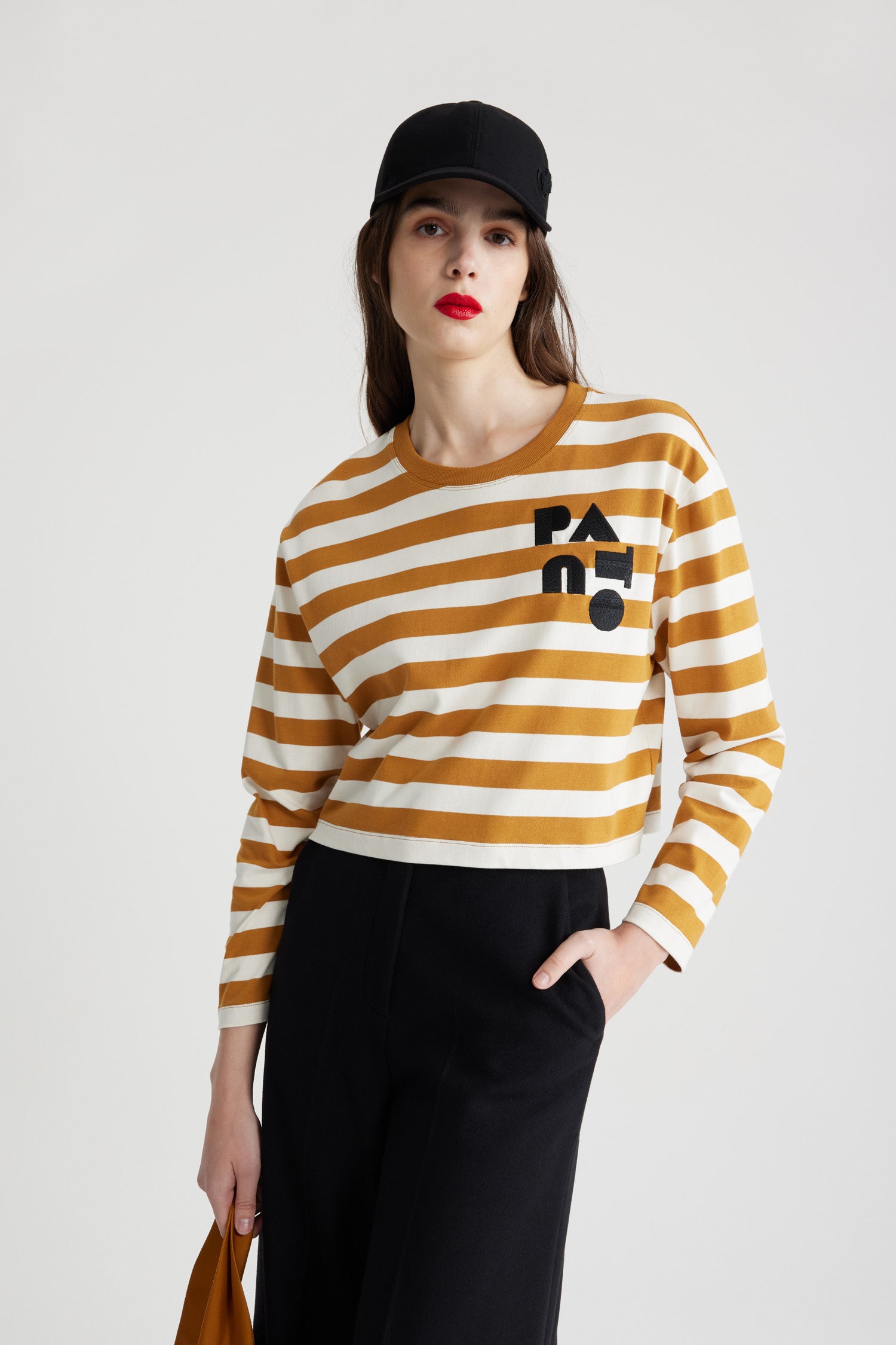 Patou - オーガニックコットン クロップド ブレトン ストライプ トップス - Beige and White - ベージュ&ホワイトのオーガニックコットン製トップス。厚手のジャージー素材。幅広のブレトンストライプ。クロップド丈。クルーネック。長袖。胸元にアール デコ調のパトゥー。クロップドスタイル。