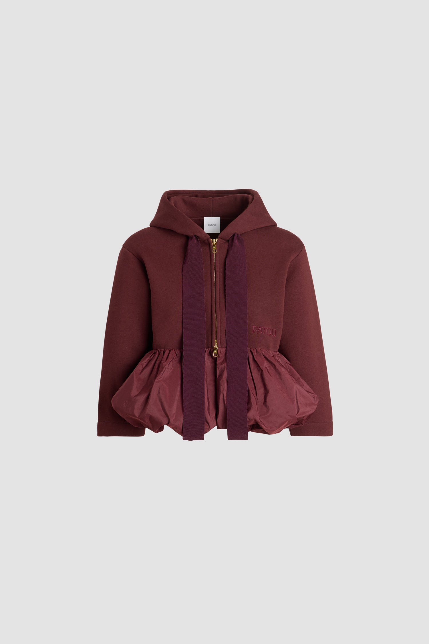 Patou - オーガニックコットン&ファイユ フリルヘム ジップアップフーディ - Syrah - シラーバーガンディのオーガニックコットン製フーディ。ポリエステルファイユ製フリル付きのペプラムシルエット。フード付き襟にグログラン ドローストリング。ゴールドトーンの2wayファスナー。フロントにパトゥの刺繍ロゴ。
