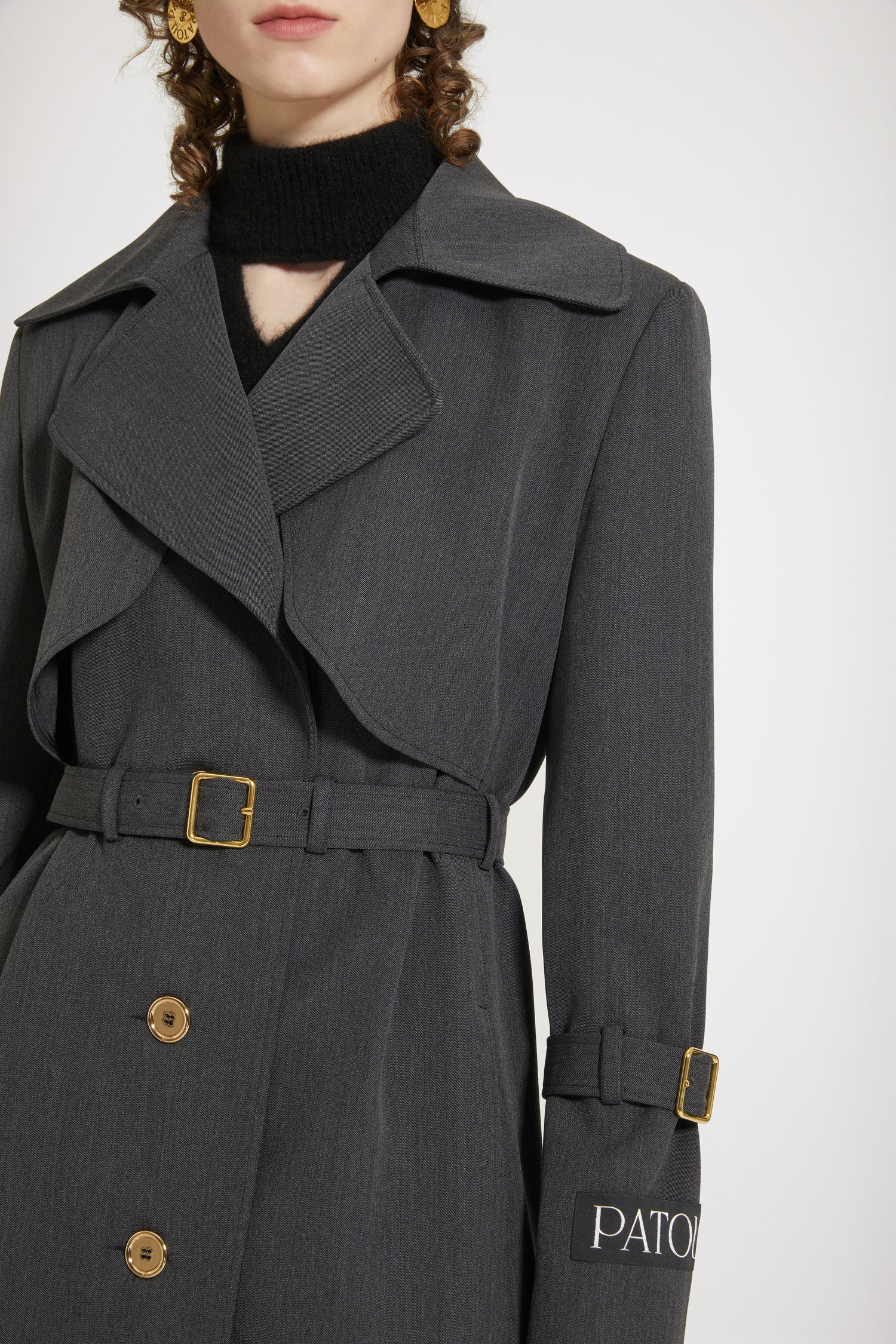 Patou - Trench coat in technical wool twill - Anthracite - The trench goes French.Anthracite grey technical wool twill trench coat. Tailored single-breasted silhouette. Knee length. Notch lapels. Storm flap at the front. Gold-tone Patou-engraved buttons at the front. Adjustable gold-tone buckle belt that sits at the waist. Side seam patch pockets at the front. Belted cuffs. Signature Patou label on the left arm. Signature curved seam at the back. Single back vent with gold-tone Patou-engraved button.