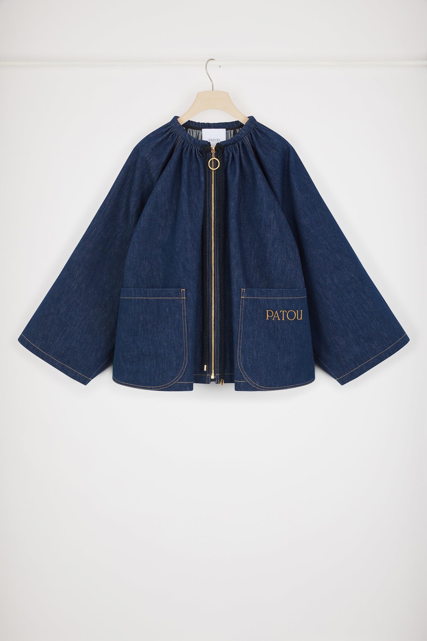 Patou - コットンデニム オーバーサイズ セーラージャケット - Rodeo Blue - たっぷりとしたボリューム感とマリンディテールが非常にパトゥらしい一着。ロデオブルーのコットンデニム製ジャケット。大きめのシルエット。ギャザーネック、編み込みのロープドローストリングにゴールドトーンのPatouエングレーブ入りの先端チップ付き。ファスナー。大きなパッチポケット。前面にPatou刺繍。オーバーサイズスタイル。