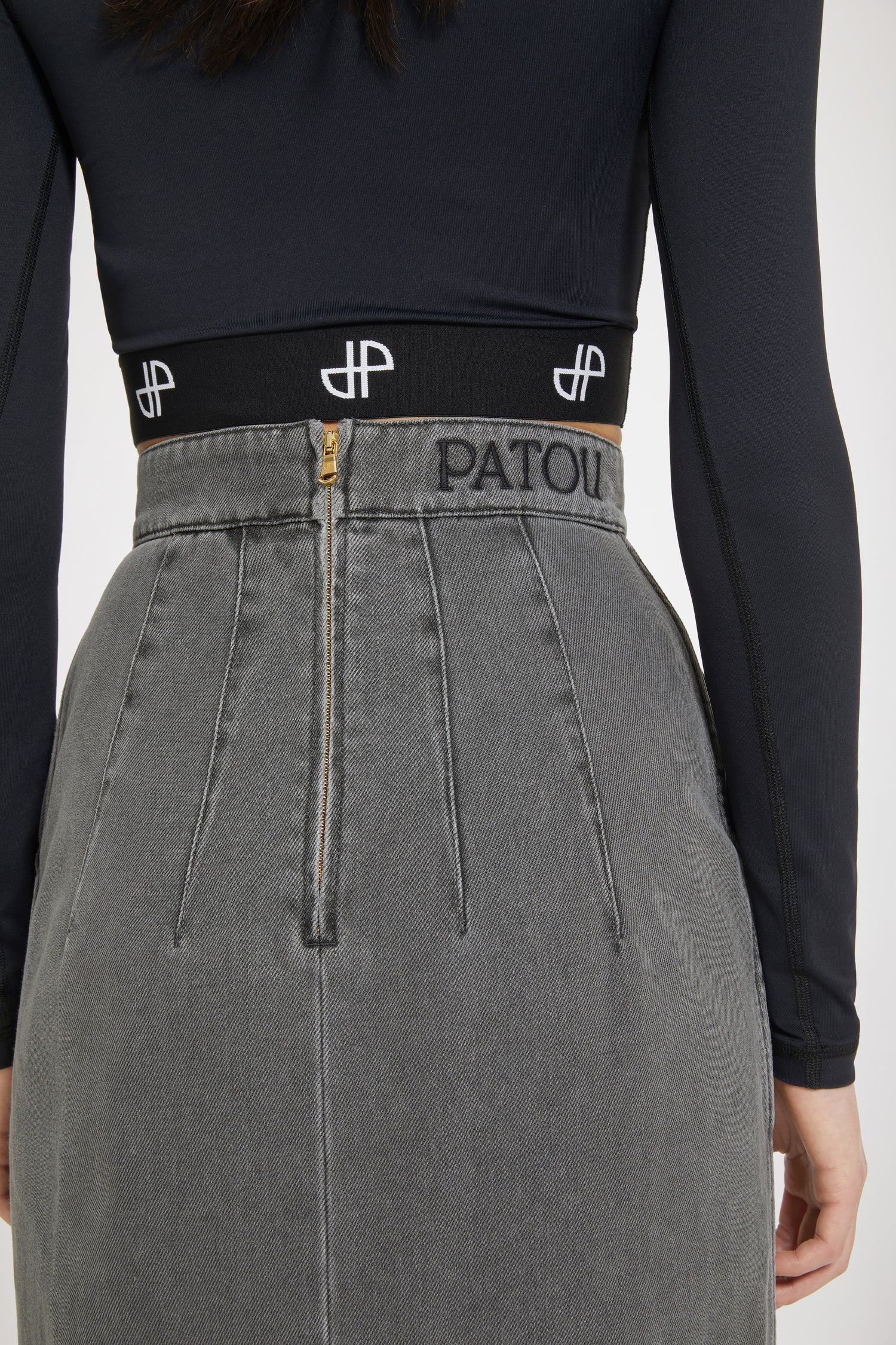 Patou - Slit midi skirt in organic cotton denim - Anthracite - The ease of denim, the allure of couture.Anthracite grey organic cotton denim skirt. Sustainable laser fading. High waist. Midi length. Fitted silhouette with multiple darts at the back. Gold-tone Patou-engraved Medallion embellishment at the front. Belt loops. High slit at the front. Pockets at the sides. Zip fastening at the back. Patou embroidery at the waist.Tight fit at the waist.The ornament can be removed.