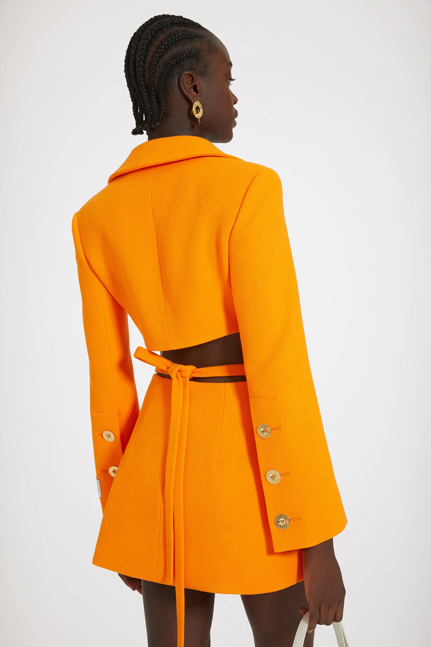 Patou - Mini jupe portefeuille en crêpe de laine - Bright Orange - Silhouette croisée, jambes sublimées.Jupe en double crêpe de laine orange vif. Taille mi-haute. Modèle court. Silhouette portefeuille évasée avec fente sur le devant. Ceinture amovible à nouer au dos. Fermeture par zip au dos.Ce modèle est très court.