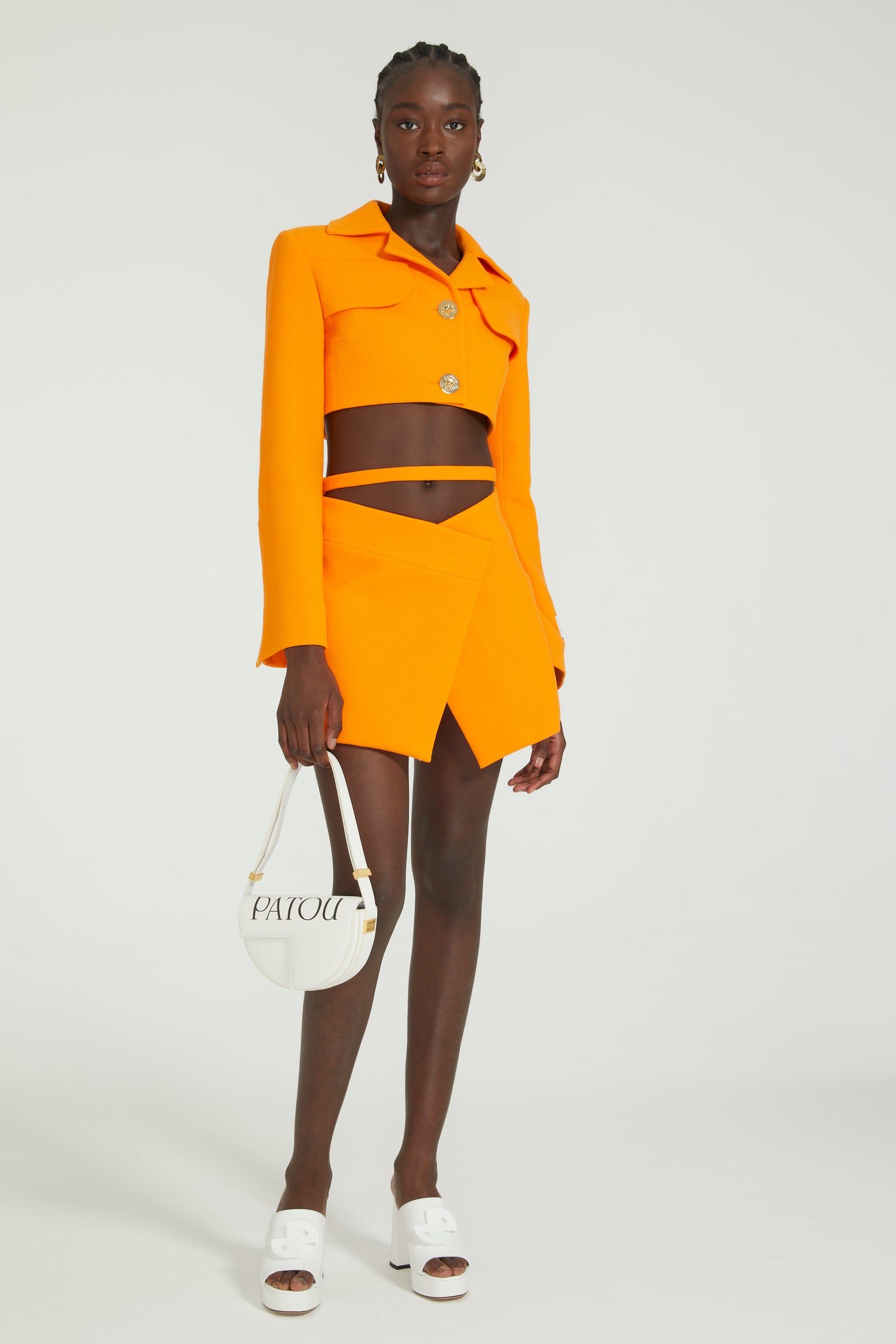 Patou - Mini jupe portefeuille en crêpe de laine - Bright Orange - Silhouette croisée, jambes sublimées.Jupe en double crêpe de laine orange vif. Taille mi-haute. Modèle court. Silhouette portefeuille évasée avec fente sur le devant. Ceinture amovible à nouer au dos. Fermeture par zip au dos.Ce modèle est très court.
