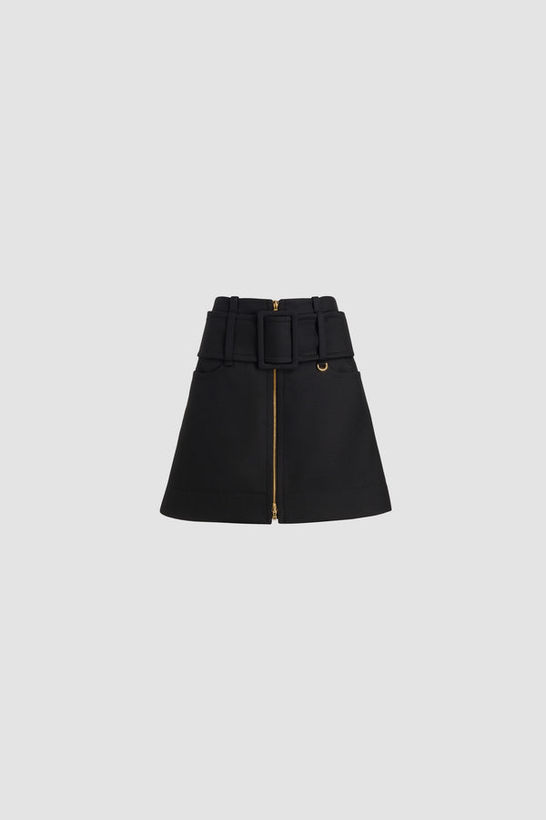 Patou - Jupe courte ceinturée zippée à l’avant en laine - Black - Jupe en laine noire. Modèle court. Taille basse. Fermeture par zip doré à double curseur à l’avant. Ceinture large en tissu sur les hanches avec boucle recouverte de tissu et anneau doré. Poches basses sur le devant. Modèle doublé.