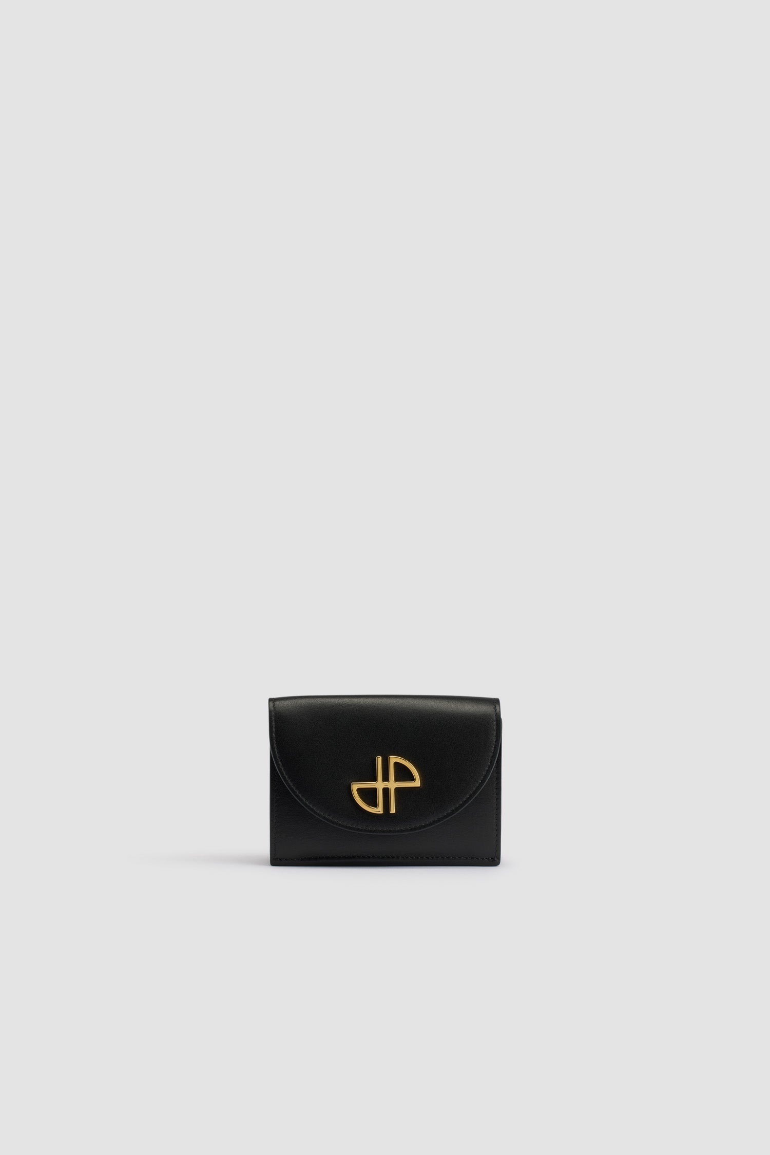 Patou - レザー JP ウォレット - Black - ブラックのレザー製ウォレット。未使用の高品質皮革を用いた独自素材を使用。前面にゴールドトーンのJP。スナップボタン開閉。カードスロット&ポケット複数、紙幣用の大きめポケット 1つ。内側にJPのカットアウトおよびゴールドエンボスのPatou。
