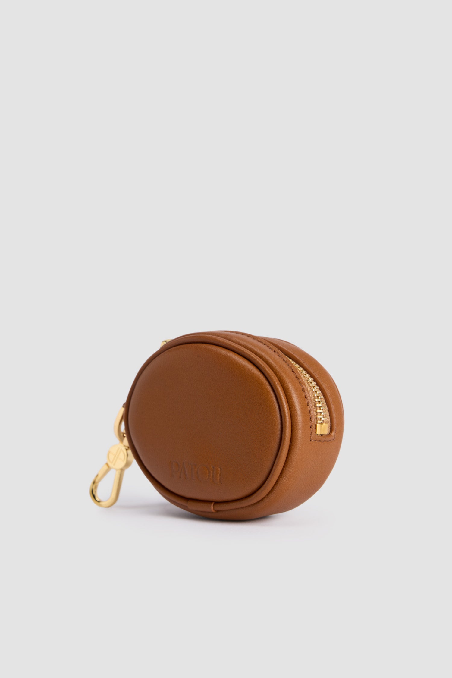Patou - Mini JP pouch in leather - Autumn Leaf - Autumn Leaf brown leather pouch. Can be used as a bag charm. Oval shape with a foam-padded 3D JP monogram at the front. Embossed Patou at the back. Zip fastening. Gold-tone hook. Designed to fit wireless earphones.