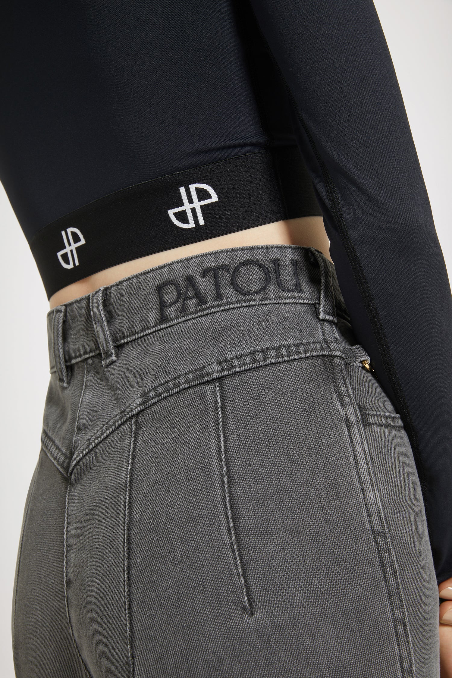 Patou - Flared trousers in organic cotton denim - Anthracite - Jean genie: denim by Patou.Anthracite grey organic cotton denim trousers. Sustainable laser fading. Flared leg. Mid rise. Gold-tone Patou-engraved button at the front. Belt loops. Embroidered Patou logo at the waistband. Darts and central creases at the front and back. Two pockets at the front with gold-tone Patou-engraved ornaments. Signature curved seam at the back.