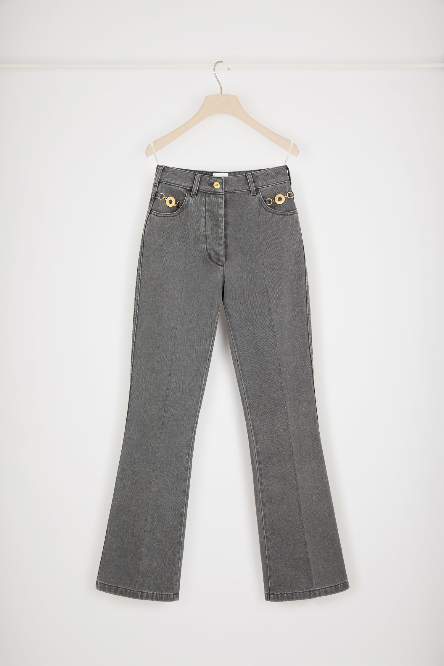 Patou - Flared trousers in organic cotton denim - Anthracite - Jean genie: denim by Patou.Anthracite grey organic cotton denim trousers. Sustainable laser fading. Flared leg. Mid rise. Gold-tone Patou-engraved button at the front. Belt loops. Embroidered Patou logo at the waistband. Darts and central creases at the front and back. Two pockets at the front with gold-tone Patou-engraved ornaments. Signature curved seam at the back.