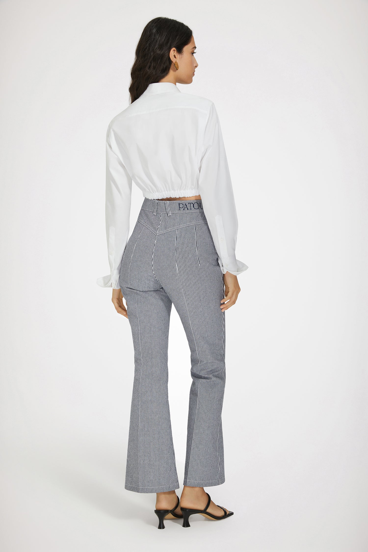 Patou - Flared trousers in striped cotton denim - Navy Striped - Jean genie: denim by Patou.Navy cotton denim trousers. Thin stripes. Flared leg. Mid rise. Gold-tone Patou-engraved button at the front. Belt loops. Embroidered Patou logo at the waistband. Darts and central creases at the front and back. Two pockets at the front with gold-tone Patou-engraved ornaments. Signature curved seam at the back.This style is very fitted at the waist.