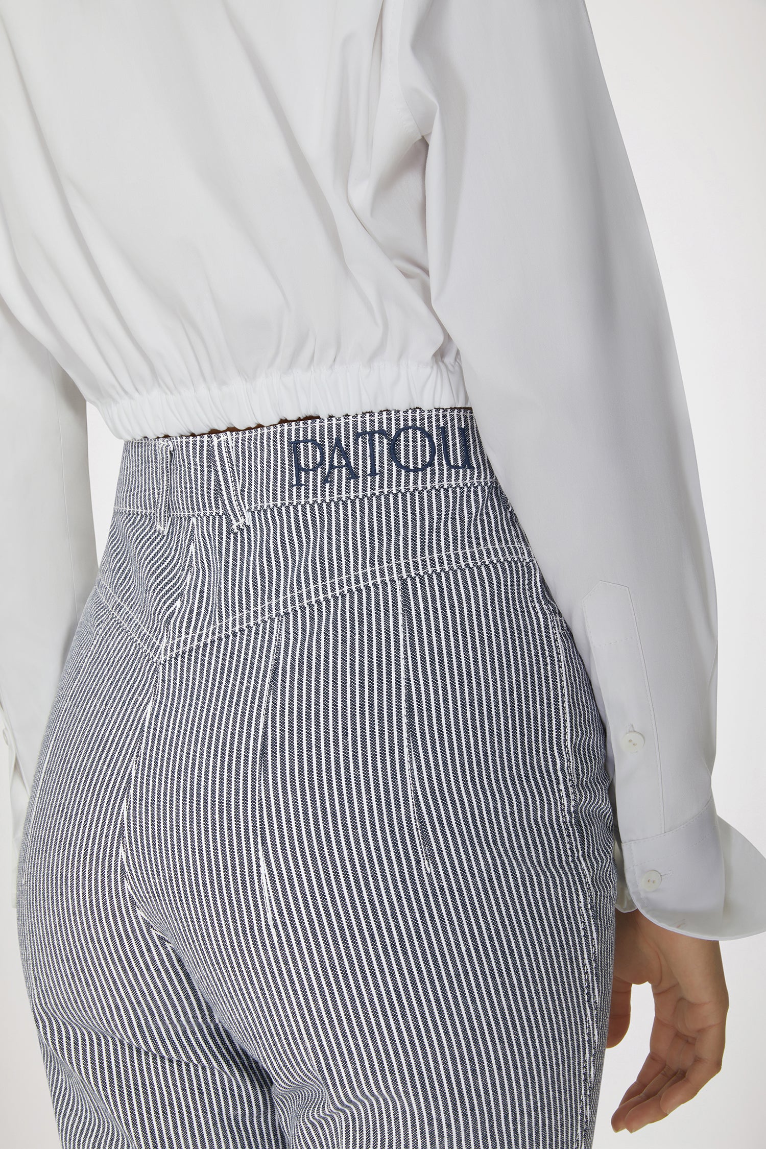 Patou - Flared trousers in striped cotton denim - Navy Striped - Jean genie: denim by Patou.Navy cotton denim trousers. Thin stripes. Flared leg. Mid rise. Gold-tone Patou-engraved button at the front. Belt loops. Embroidered Patou logo at the waistband. Darts and central creases at the front and back. Two pockets at the front with gold-tone Patou-engraved ornaments. Signature curved seam at the back.This style is very fitted at the waist.