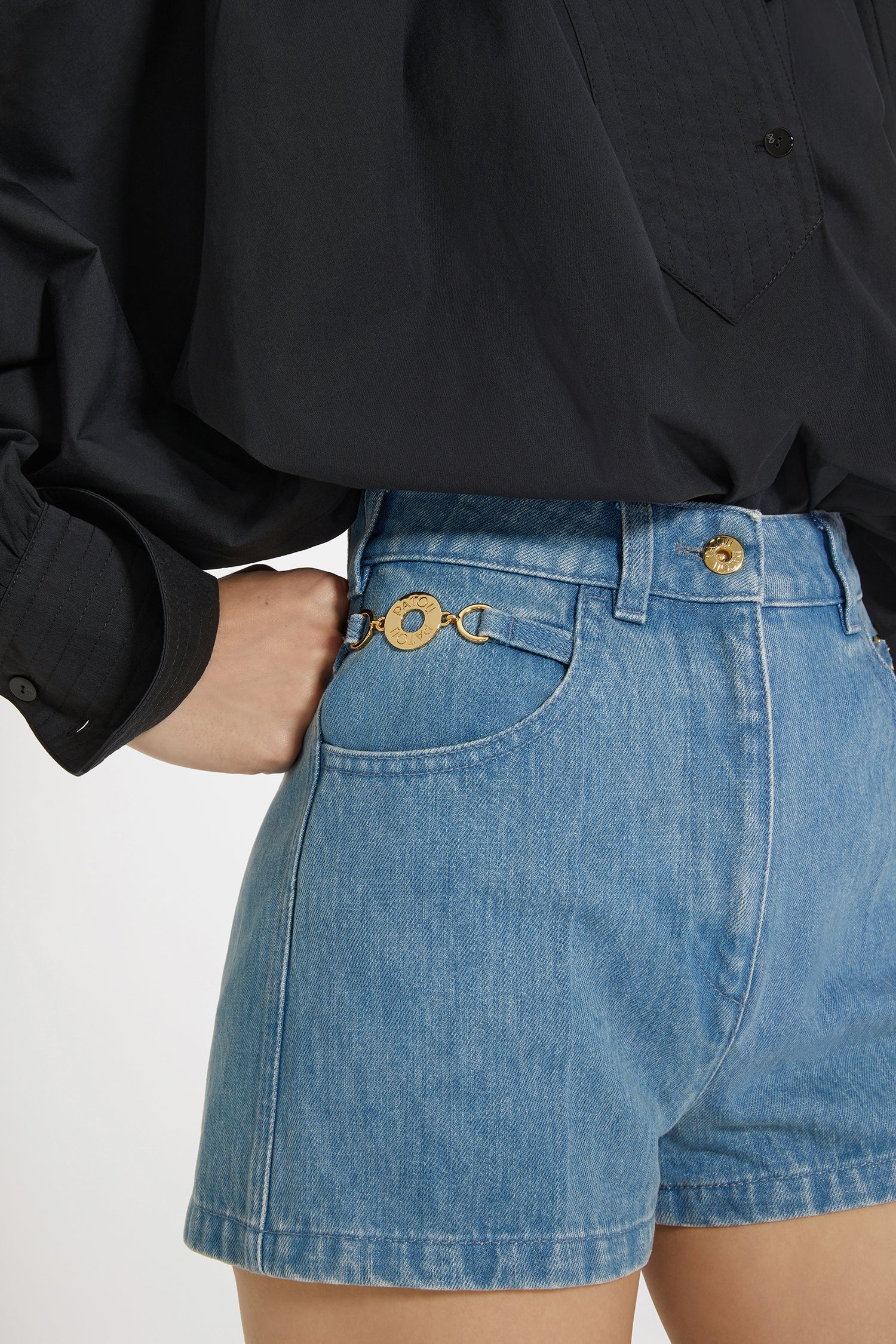 Patou - コットンデニム ミニショートパンツ - Ice Blue - ミニなのに存在感たっぷり。アイスブルーのコットンデニム製ショートパンツ。ハイウエスト。ミニ丈。フロントにゴールドトーンのパトゥ刻印入りメダリオン装飾。フロントにゴールドトーンのパトゥ刻印入りボタン。ベルトループ付き。サイドにポケット。ウエストにパトゥの刺繍。バックにVシーム。