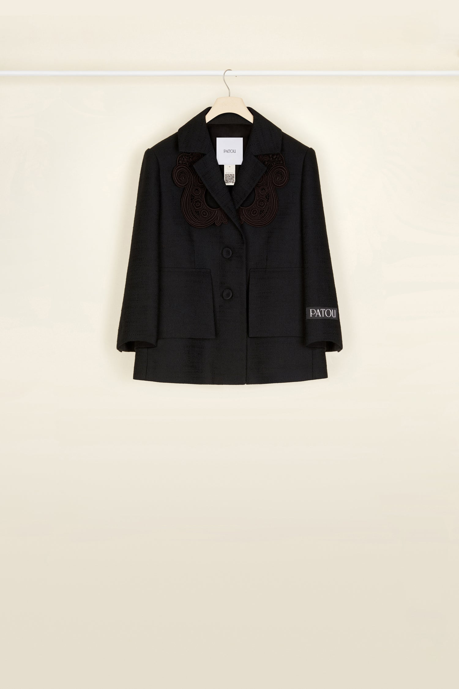 Patou - Veste courte en tweed bio avec détail en guipure - Black - La guipure qui donne de l’allure !Veste en tweed de coton et laine bio noir. Silhouette courte et ample avec fente au dos. Détails en guipure ton-sur-ton autour de l’encolure. Fermeture par deux boutons recouverts de tissus sur le devant. Étiquette blanche brodée Patou sur la manche gauche. Fausses poches à rabat. Entièrement doublée.