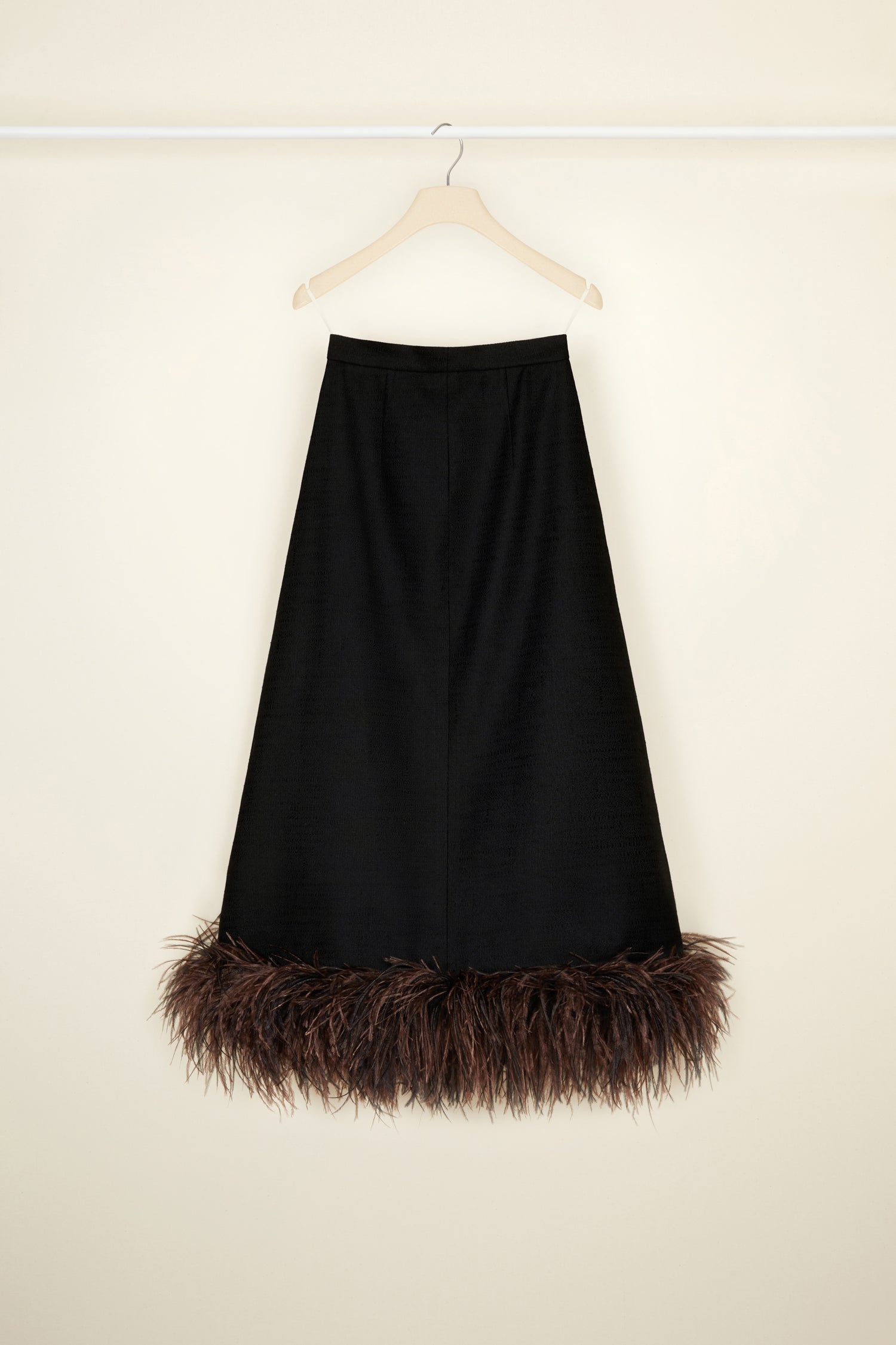 Patou - Jupe midi en tweed bio et plumes - Black - Léger comme une plume, on le porte partout : le tweed selon Patou.Jupe en tweed de coton et laine bio noir. Longueur midi. Boutons recouverts de tissus sur le devant. Poches latérales. Ourlet décoré de plumes d’autruche marron.