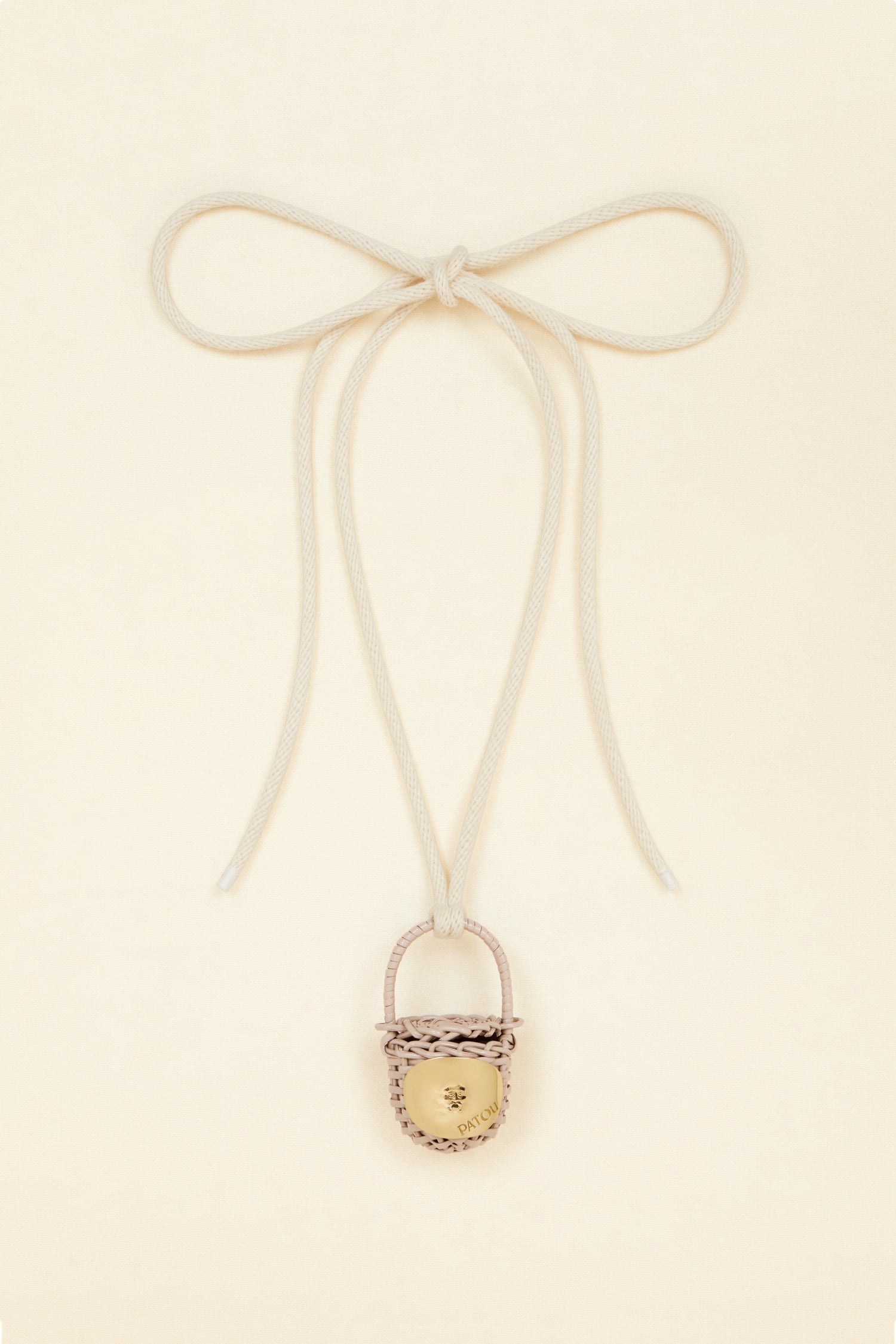 Patou - Bucket bag necklace in wicker - Parchment - A shiny amulet to carry your Patou everywhere with you. Ecru cord necklace with miniature wicker bucket bag pendant in Parchment beige. Top handle with a sliding lid. Gold-tone embellishment inspired by the Bocca della Verità"."