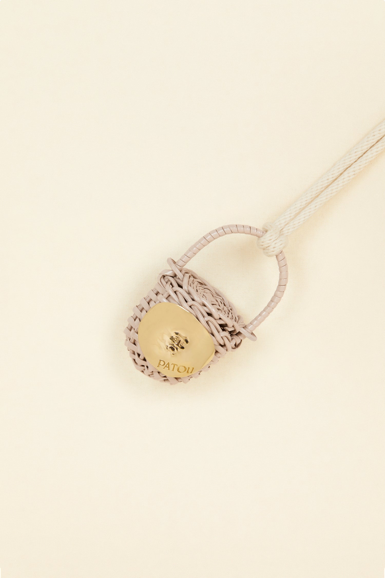 Patou - Bucket bag necklace in wicker - Parchment - A shiny amulet to carry your Patou everywhere with you. Ecru cord necklace with miniature wicker bucket bag pendant in Parchment beige. Top handle with a sliding lid. Gold-tone embellishment inspired by the Bocca della Verità"."