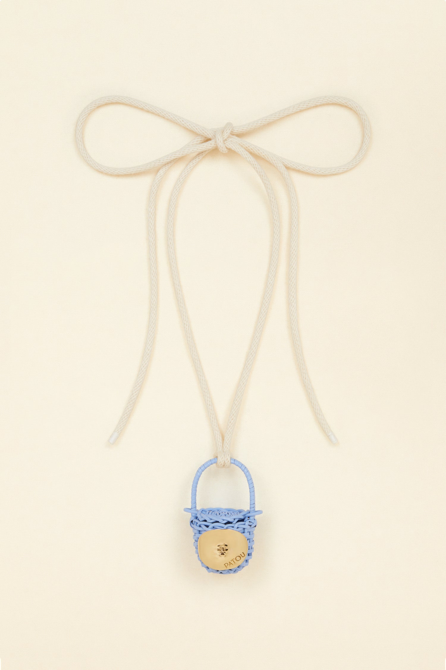 Patou - Bucket bag necklace in wicker - Aurora - A shiny amulet to carry your Patou everywhere with you. Ecru cord necklace with miniature wicker bucket bag pendant in Aurora light blue. Top handle with a sliding lid. Gold-tone embellishment inspired by the Bocca della Verità"."