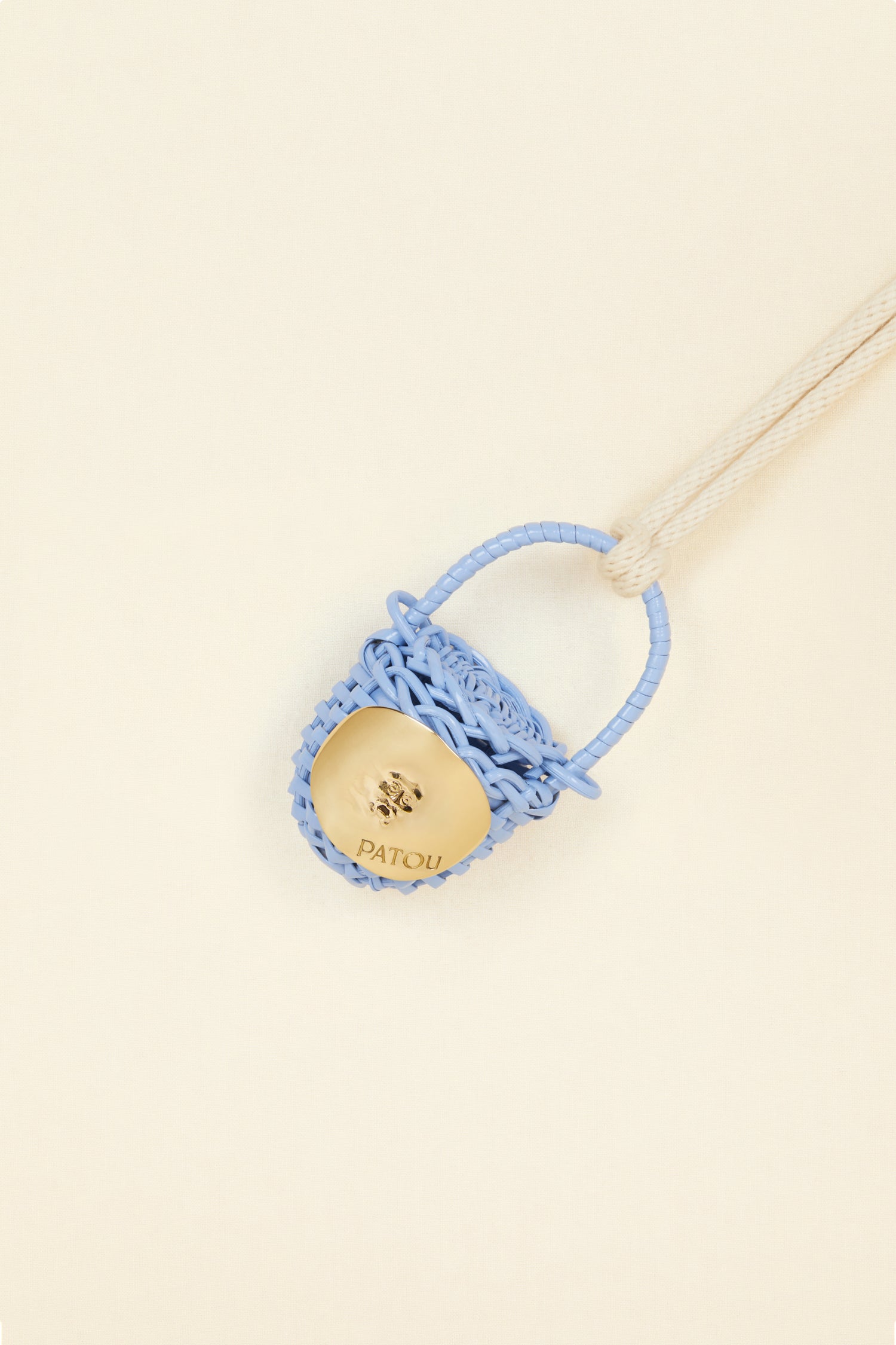 Patou - Bucket bag necklace in wicker - Aurora - A shiny amulet to carry your Patou everywhere with you. Ecru cord necklace with miniature wicker bucket bag pendant in Aurora light blue. Top handle with a sliding lid. Gold-tone embellishment inspired by the Bocca della Verità"."