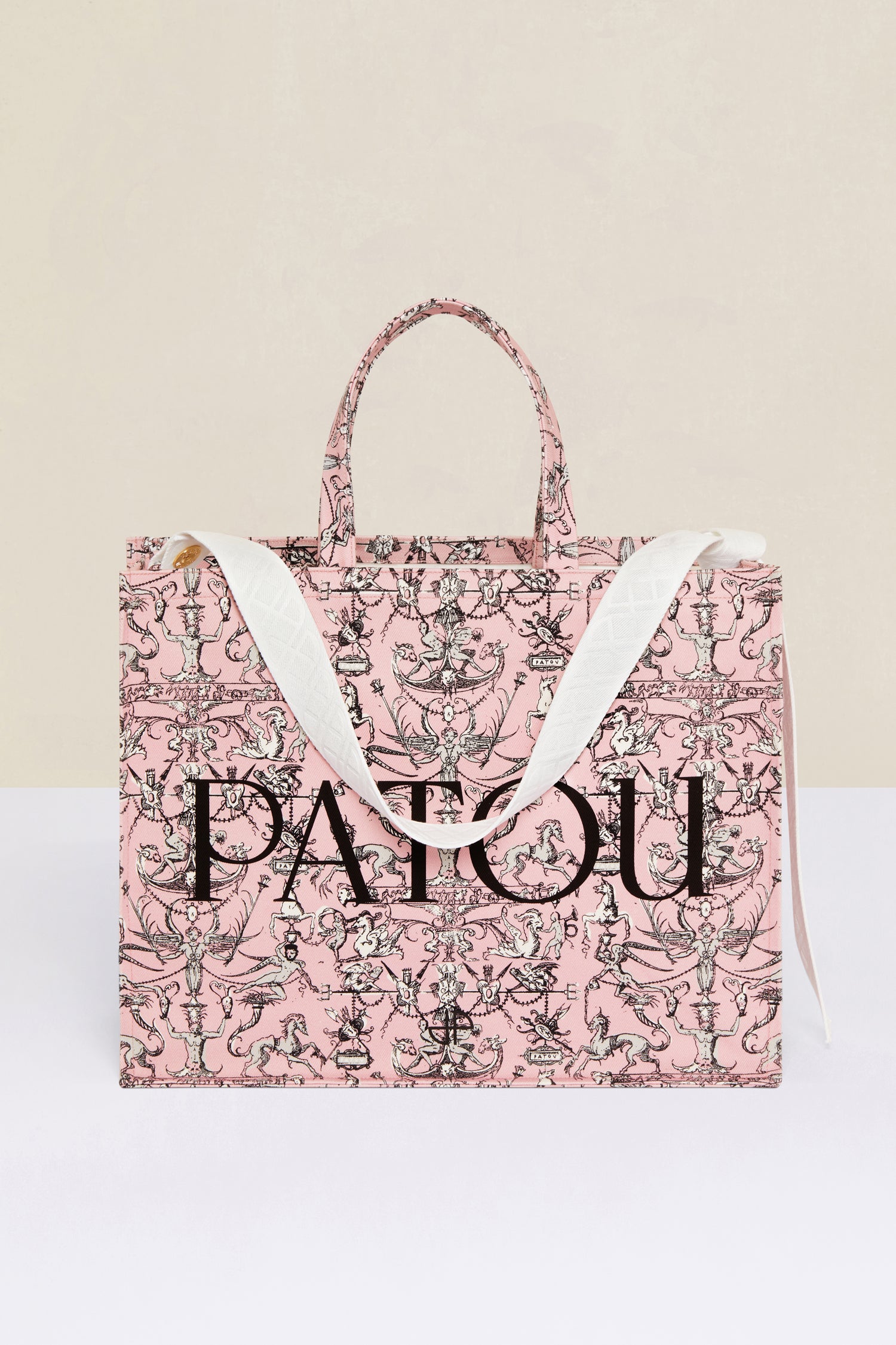 Patou - Patou canvas tote in printed organic cotton - Pink Fairy Tales - A tale of essential designs and fantastical motifs.Pink organic cotton tote. “Stories and Tales” seasonal print. Patou lettering logo and JP monogram in black. White embossed shoulder strap with gold button on one side and adjustable knot on the other side. Two tone-on-tone top handles. Can be carried by hand or on the shoulder.