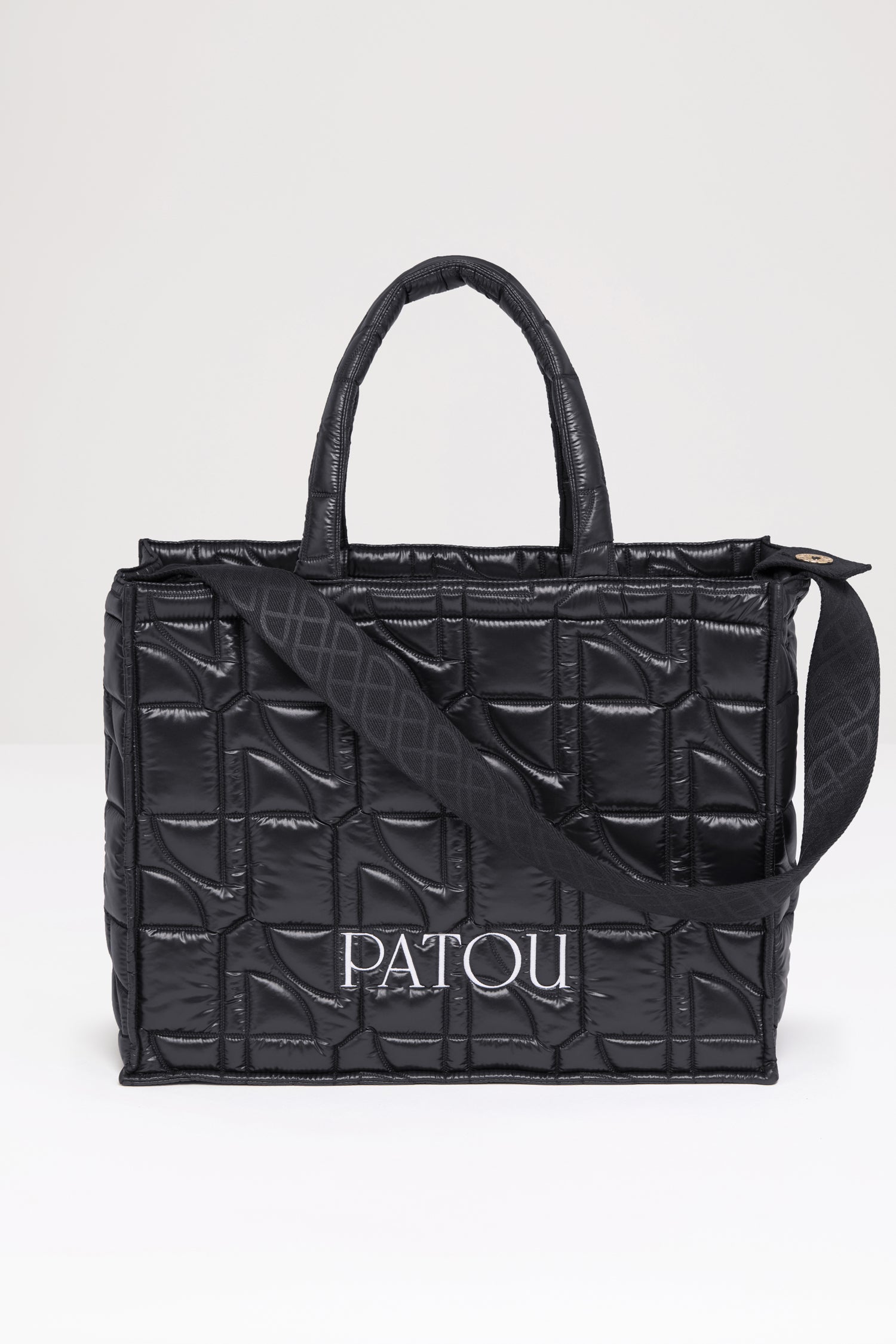 Patou - 파투 퀼티드 토트백 - Black - 어디든 휴대하기 쉬운 파투의 토트백. 블랙 컬러 폴리아미드 소재 토트백. JP 올오버 퀼팅. 화이트 컬러의 Patou 레터링 로고. Patou가 새겨진 골드 버튼으로 양쪽 측면에 부착된 블랙 컬러의 엠보싱 숄더 스트랩. 두 개의 탑 핸들. 토트백 또는 숄더백으로 착용 가능.
