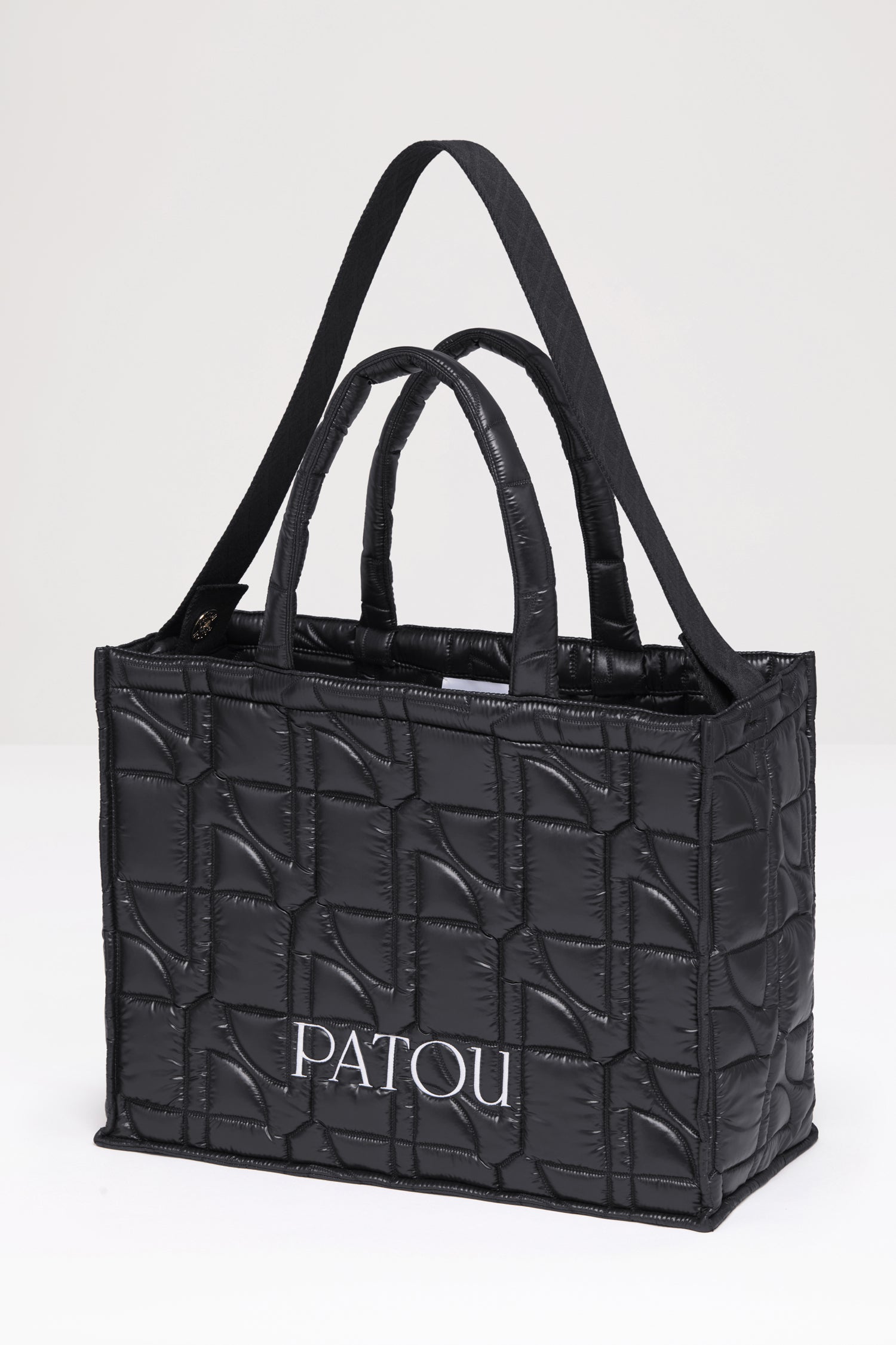 Patou - 파투 퀼티드 토트백 - Black - 어디든 휴대하기 쉬운 파투의 토트백. 블랙 컬러 폴리아미드 소재 토트백. JP 올오버 퀼팅. 화이트 컬러의 Patou 레터링 로고. Patou가 새겨진 골드 버튼으로 양쪽 측면에 부착된 블랙 컬러의 엠보싱 숄더 스트랩. 두 개의 탑 핸들. 토트백 또는 숄더백으로 착용 가능.