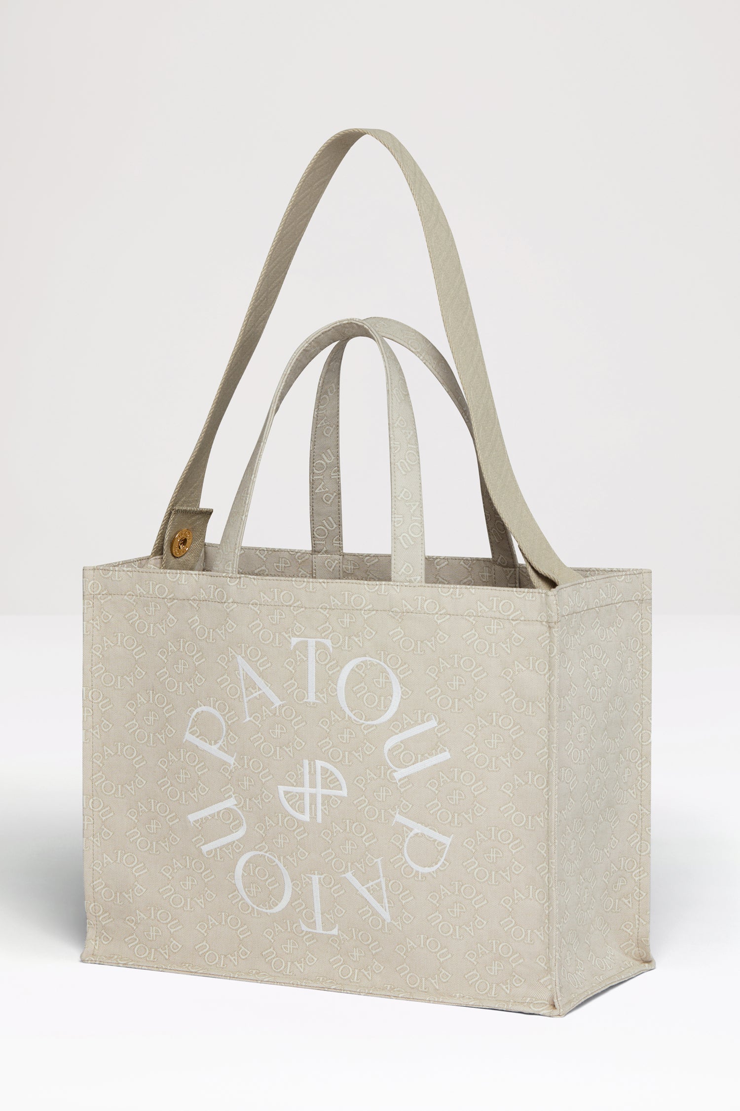 Patou - Patou canvas tote in organic cotton jacquard - Medallion - Carry your Patou everywhere with you. Organic cotton jacquard tote. Seasonal Medallion pattern featuring the Patou lettering logo and JP monogram all over. Patou lettering logo and JP monogram in white. Embossed shoulder strap with gold buttons. Two top handles. Can be carried by hand or on the shoulder.