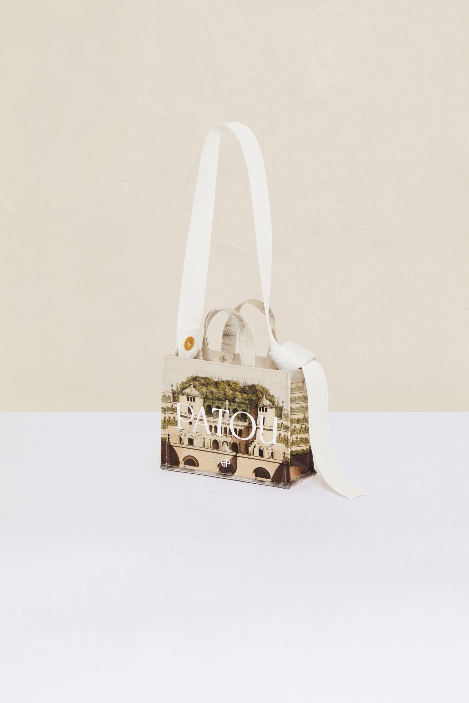Patou - Small Patou canvas tote in printed organic cotton - Amour Island - A little Patou goes a long way.Organic cotton tote featuring Jean-Jacques Lequeu's “Amour Island” print. Patou lettering logo and JP monogram in white. White embossed shoulder strap with gold button on one side and adjustable knot on the other side. Two tone-on-tone top handles. Can be carried by hand or on the shoulder.