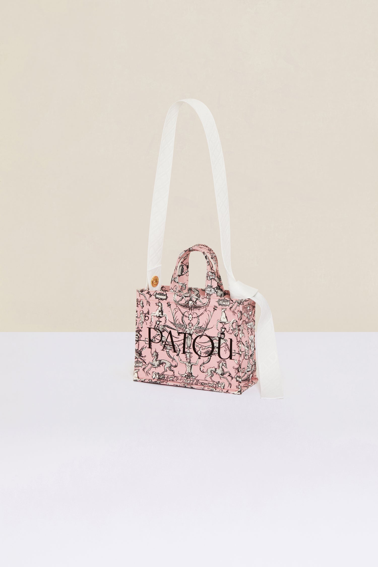 Patou - Small Patou canvas tote in printed organic cotton - Pink Fairy Tales - A tale of organic canvas and magical prints.Pink organic cotton tote. “Stories and Tales” seasonal print. Patou lettering logo and JP monogram in black. White embossed shoulder strap with gold button on one side and adjustable knot on the other side. Two tone-on-tone top handles. Can be carried by hand or on the shoulder.