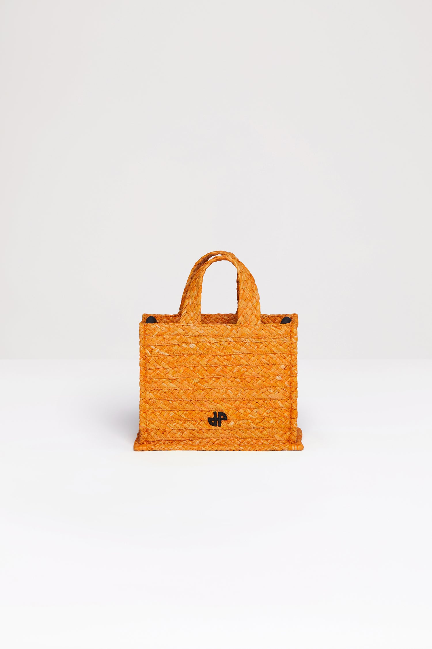 Patou - Small JP tote in raffia - Marigold - A summer classic infused with Patou magic.Marigold orange raffia tote. JP monogram in black at the front. Black embossed canvas shoulder strap with gold buttons. Two top handles. Can be carried by hand or on the shoulder.