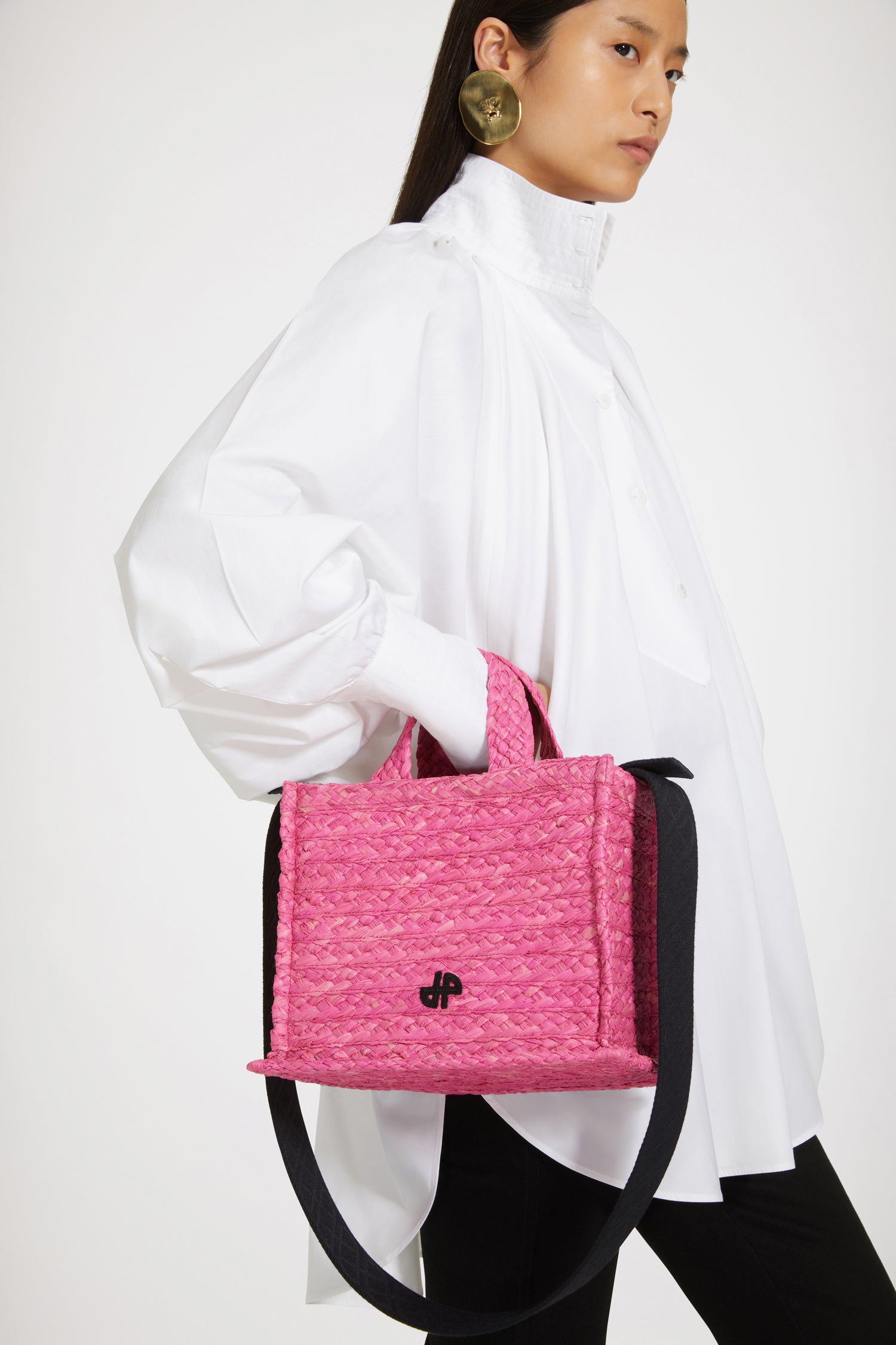 Patou - Small JP tote in raffia - Begonia Pink - A summer classic infused with Patou magic.Begonia pink raffia tote. JP monogram in black at the front. Black embossed canvas shoulder strap with gold buttons. Two top handles. Can be carried by hand or on the shoulder.