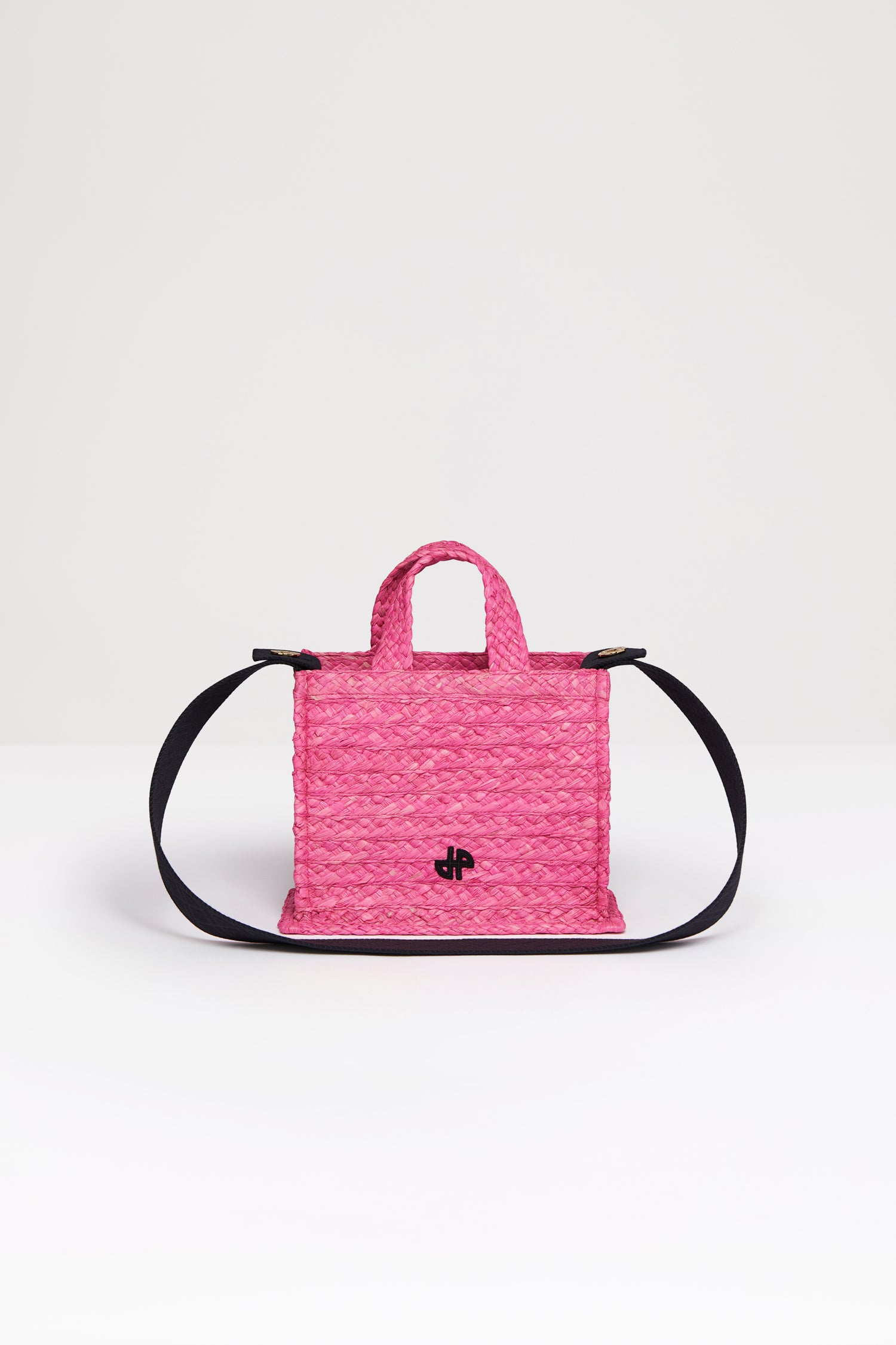 Patou - Small JP tote in raffia - Begonia Pink - A summer classic infused with Patou magic.Begonia pink raffia tote. JP monogram in black at the front. Black embossed canvas shoulder strap with gold buttons. Two top handles. Can be carried by hand or on the shoulder.