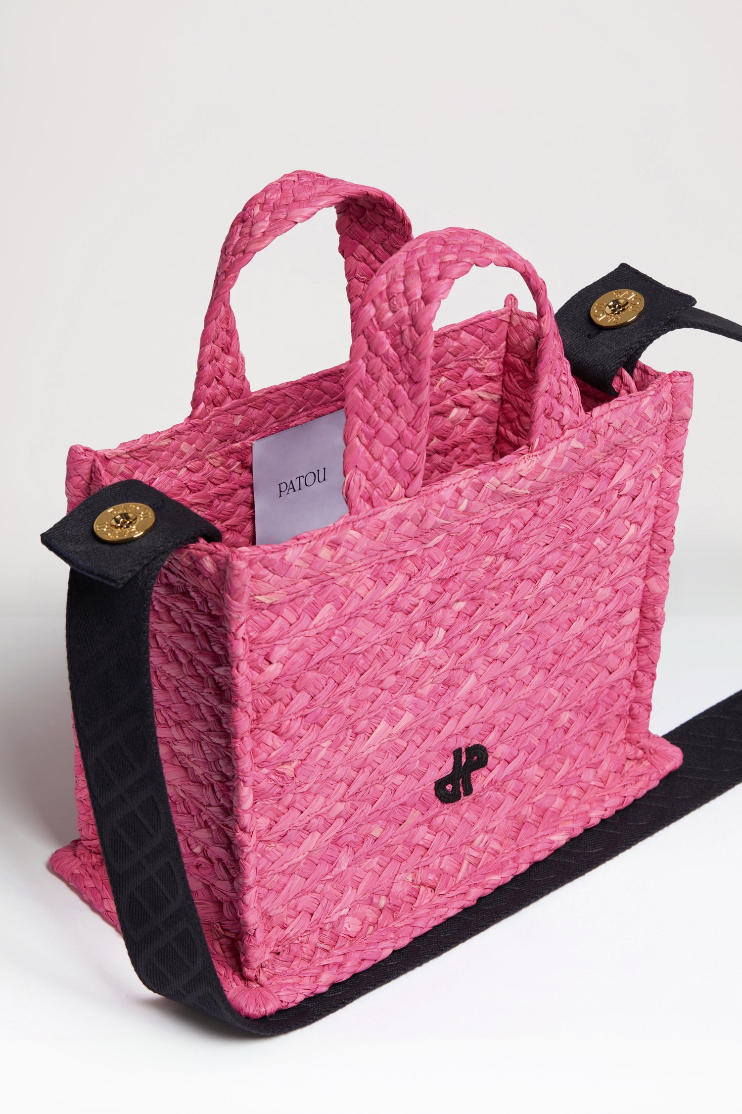 Patou - Small JP tote in raffia - Begonia Pink - A summer classic infused with Patou magic.Begonia pink raffia tote. JP monogram in black at the front. Black embossed canvas shoulder strap with gold buttons. Two top handles. Can be carried by hand or on the shoulder.