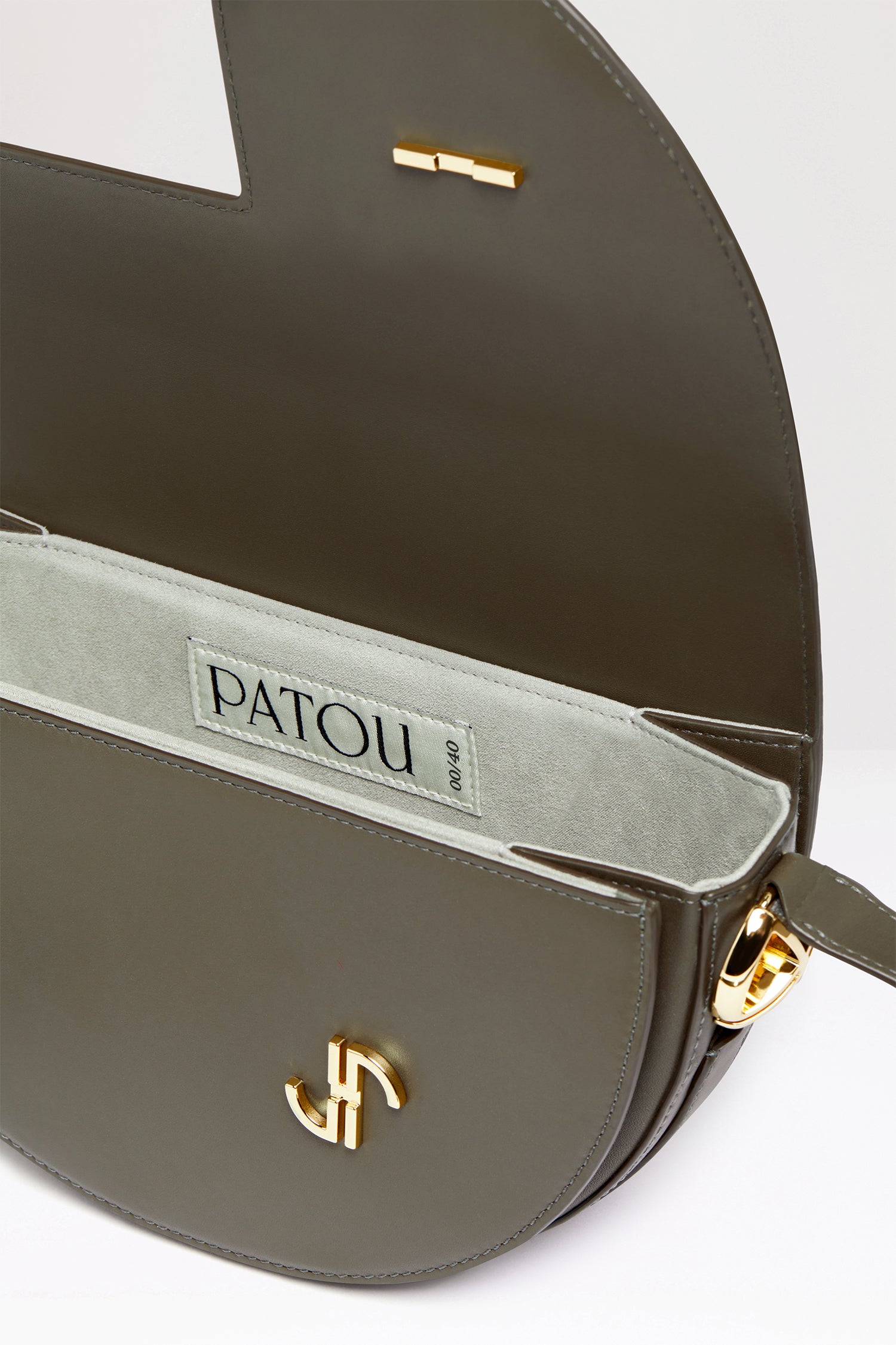 Patou - Le Patou バッグ - Winter Moss - バッグを超えたパトゥ バッグ!ウィンターモスグリーンのレザーハンドバッグ。未使用レザーから持続可能な方法により調達した独自の素材で作られた限定エディション。番号入り40 点限定エディション。JPモノグラムにインスピレーションを得た幾何学的なカットアウトをあしらった半円形のフォルム。サイドにゴールドトーンのメタルパーツとJPモノグラム ディテール。調整可能なストラップで、ショルダーバッグ、クロスボディバッグ、ハンドバッグとしてお使いいただけます。ゴールドトーンのJPディテールをあしらったマグネットクロージャー。内部に複数のコンパートメント。エコライニング。長さ: 25 cm高さ: 15 cm幅:6 cmストラップの長さは3段階で調節可能:47 cm (ショルダー)、36 cm (クロスボディ)、28 cm (ハンド)