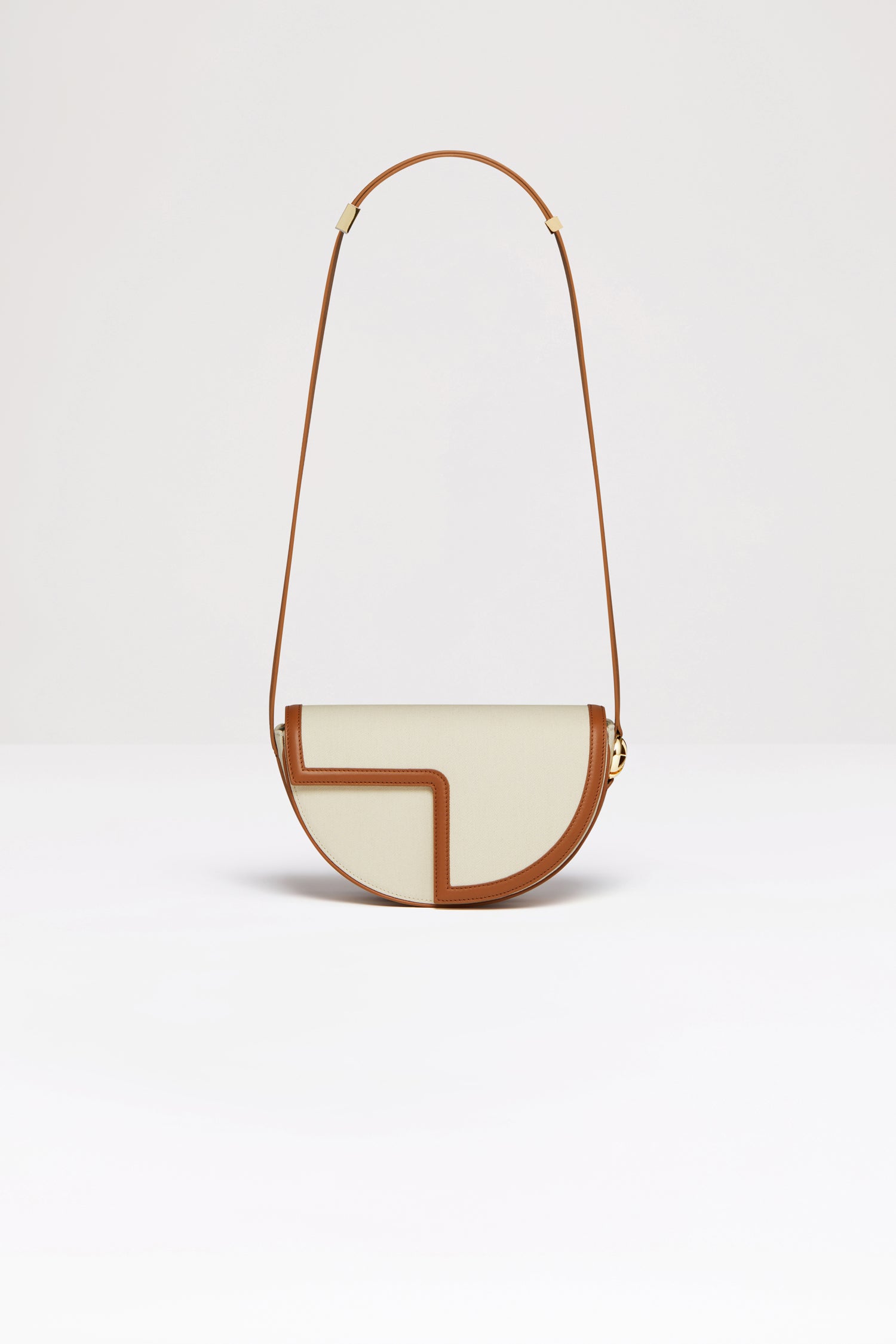 Patou - Le Patou bag in recycled cotton and leather - Saffron Clay - A new take on Le Patou that is bound to delight you. Natural recycled cotton canvas and Saffron Clay brown leather handbag. All leather parts sourced from unused high quality leather hides. 120 limited numbered edition. Half-circle shape with geometric cut-outs inspired by the JP monogram. Gold-tone hardware with JP monogram detail at the side. Adjustable strap that allows it to be worn on the shoulder, across the body or carried by hand. Magnetic closure with gold-tone JP detail. Multiple compartments inside.Measures: 25cm (length), 15cm (height), 6cm (depth)3 lengths for the adjustable strap: 47 cm (on the shoulder), 36 cm (across the body), 28 cm (carried by hand).