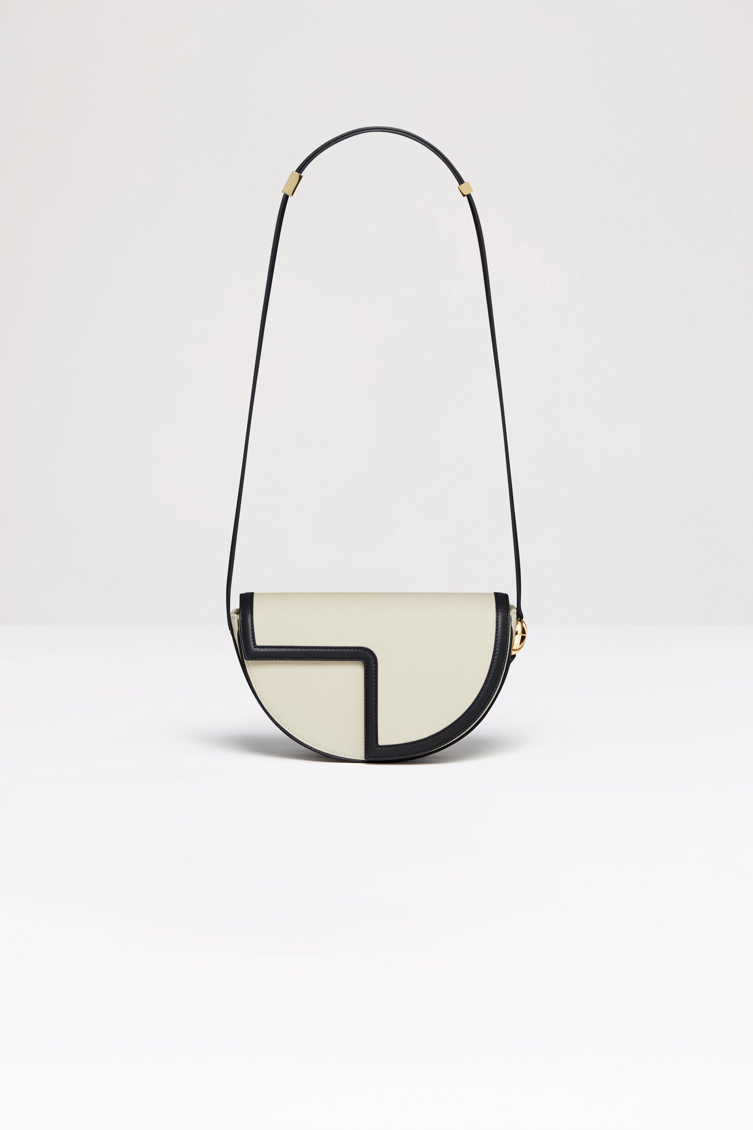 Patou - Le Patou bag in recycled cotton and leather - Black - A new take on Le Patou that is bound to delight you. Natural recycled cotton canvas and black leather handbag. All leather parts sourced from unused high quality leather hides. 40 limited numbered edition. Half-circle shape with geometric cut-outs inspired by the JP monogram. Gold-tone hardware with JP monogram detail at the side. Adjustable strap that allows it to be worn on the shoulder, across the body or carried by hand. Magnetic closure with gold-tone JP detail. Multiple compartments inside.Measures: 25cm (length), 15cm (height), 6cm (depth)3 lengths for the adjustable strap: 47 cm (on the shoulder), 36 cm (across the body), 28 cm (carried by hand).