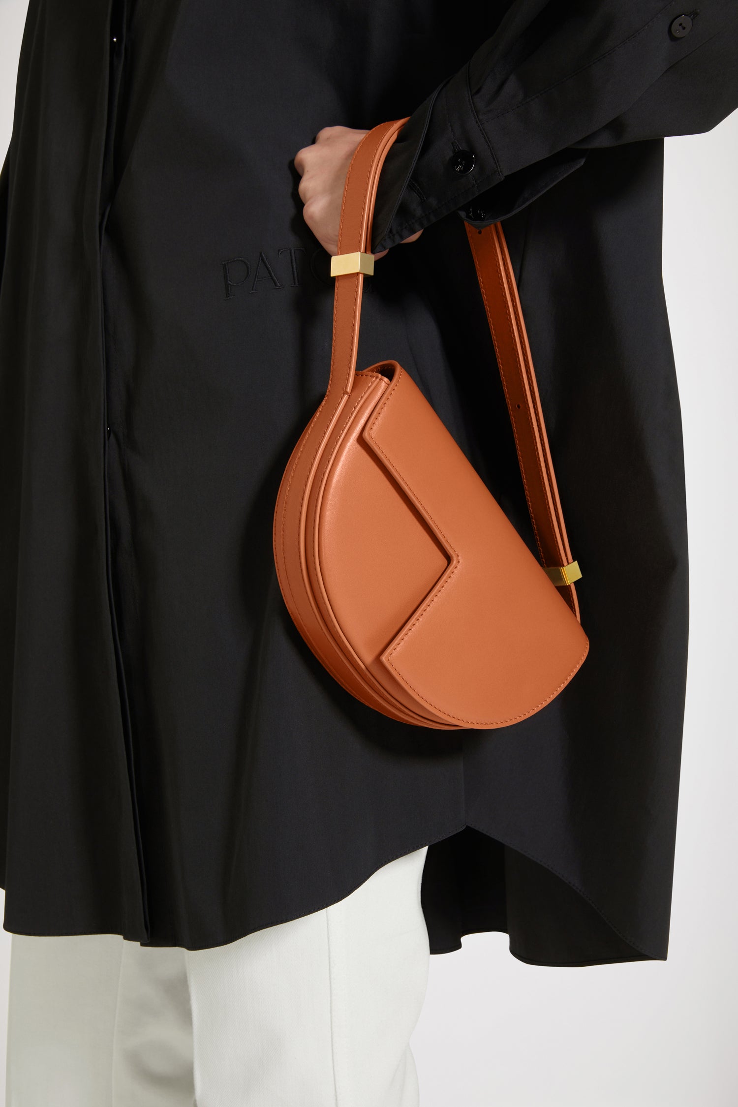 Patou - Le Petit Patou - Saffron Clay - A smaller take on everyone's favourite piece of Patou!Saffron Clay tan leather handbag. Crafted using unique materials sourced from unused high quality leather hides. 120 limited numbered edition. Half-circle shape with geometric cut-outs inspired by the JP monogram. Gold-tone hardware with JP monogram detail at the side. Adjustable strap that allows it to be worn on the shoulder, across the body or carried by hand. Magnetic closure with gold-tone JP detail. Multiple compartments inside. Eco lining.Measures: 20cm (length), 13cm (height), 5cm (depth)