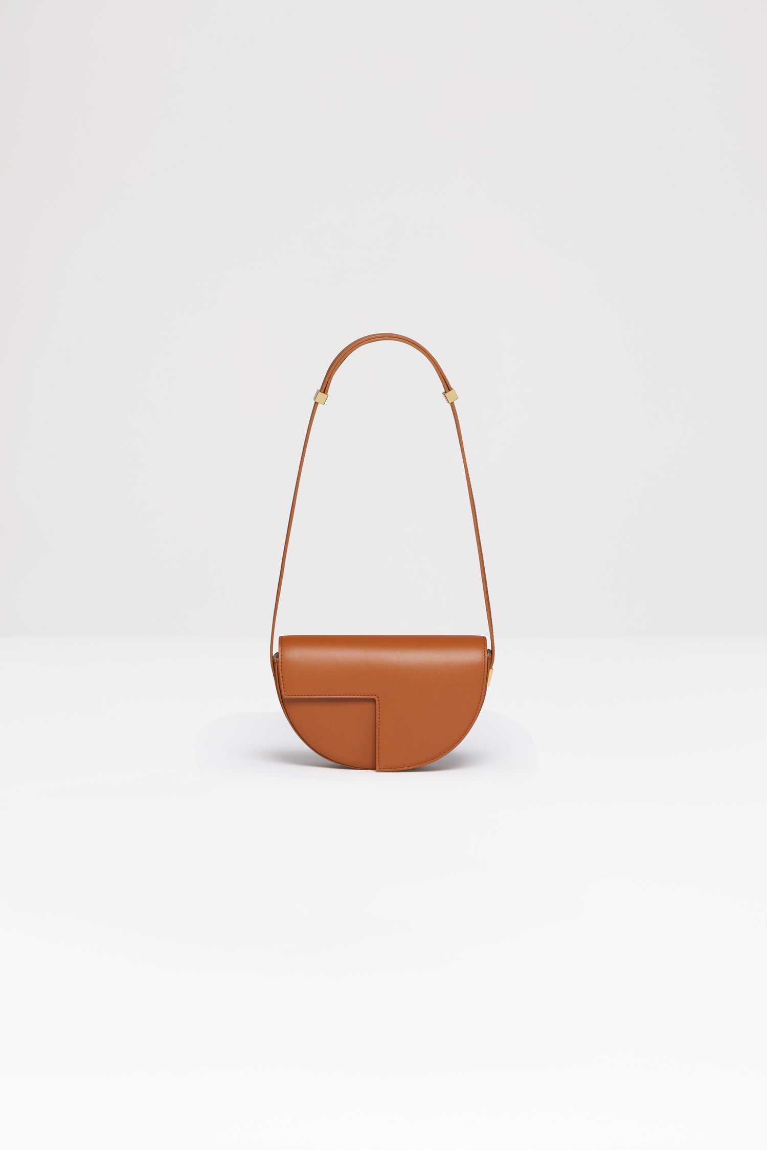 Patou - Le Petit Patou - Saffron Clay - A smaller take on everyone's favourite piece of Patou!Saffron Clay tan leather handbag. Crafted using unique materials sourced from unused high quality leather hides. 120 limited numbered edition. Half-circle shape with geometric cut-outs inspired by the JP monogram. Gold-tone hardware with JP monogram detail at the side. Adjustable strap that allows it to be worn on the shoulder, across the body or carried by hand. Magnetic closure with gold-tone JP detail. Multiple compartments inside. Eco lining.Measures: 20cm (length), 13cm (height), 5cm (depth)