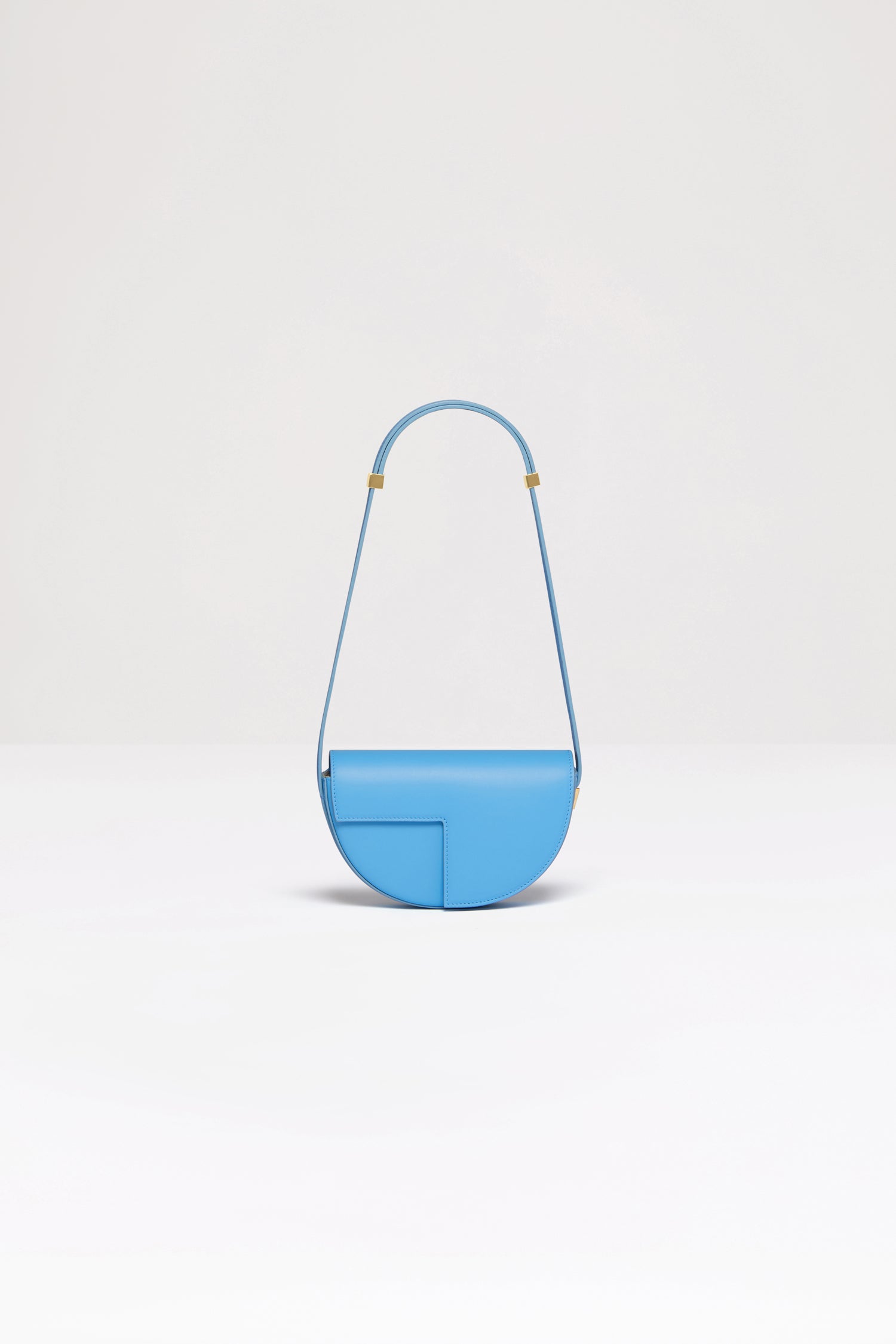 Patou - Le Petit Patou バッグ - Blue Lagon - みんなのお気に入りのLe Patouのスモールバージョンです!ブルーラゴンのレザーハンドバッグ。未使用レザーから持続可能な方法により調達した独自の素材で作られた限定エディション。番号入り120点限定エディション。JPモノグラムにインスピレーションを得た幾何学的なカットアウトをあしらった半円形のフォルム。サイドにゴールドトーンのメタルパーツとJPモノグラム ディテール。調整可能なストラップで、ショルダーバッグ、クロスボディバッグ、ハンドバッグとしてお使いいただけます。ゴールドトーンのJPディテールをあしらったマグネットクロージャー。内部に複数のコンパートメント。エコライニング。長さ: 20 cm 高さ:13 cm 幅:5 cm