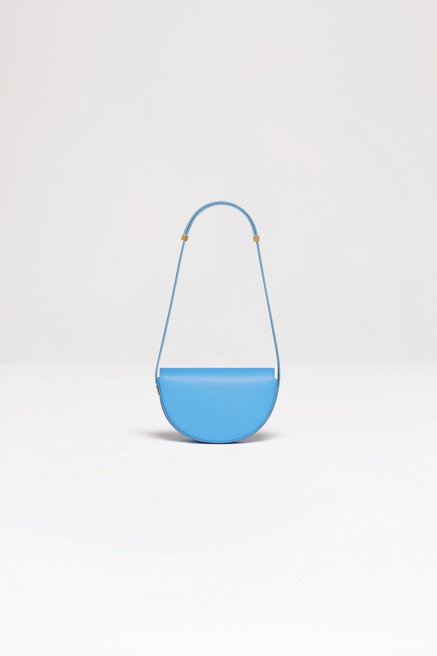 Patou - Le Petit Patou バッグ - Blue Lagon - みんなのお気に入りのLe Patouのスモールバージョンです!ブルーラゴンのレザーハンドバッグ。未使用レザーから持続可能な方法により調達した独自の素材で作られた限定エディション。番号入り120点限定エディション。JPモノグラムにインスピレーションを得た幾何学的なカットアウトをあしらった半円形のフォルム。サイドにゴールドトーンのメタルパーツとJPモノグラム ディテール。調整可能なストラップで、ショルダーバッグ、クロスボディバッグ、ハンドバッグとしてお使いいただけます。ゴールドトーンのJPディテールをあしらったマグネットクロージャー。内部に複数のコンパートメント。エコライニング。長さ: 20 cm 高さ:13 cm 幅:5 cm