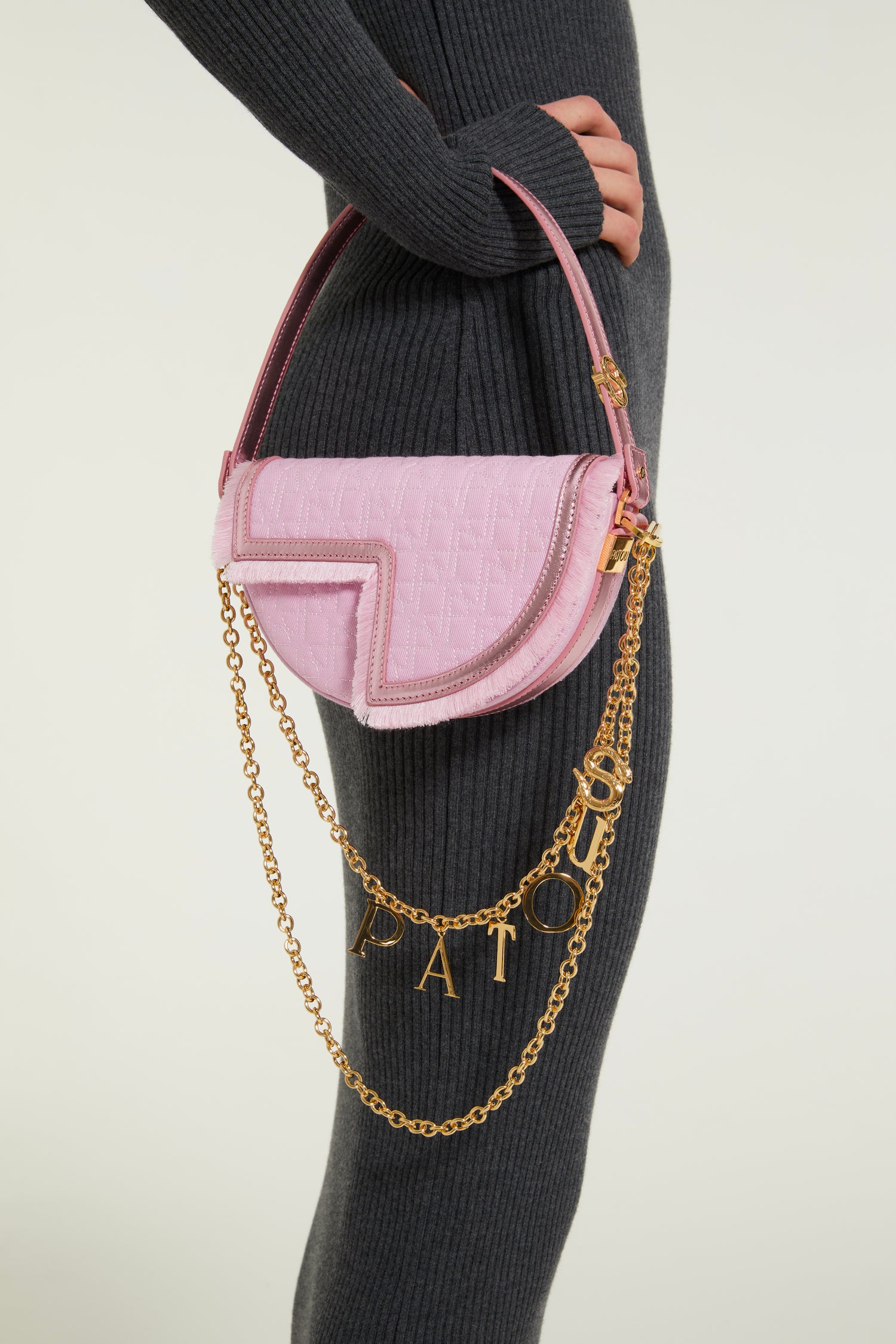 Patou - Le Petit Patou x Sita - Pink - Remixé et revisité, le Petit Patou plus culte que jamais !Sac en coton bio recyclé effet denim et cuir métallisé rose. Créé dans le cadre de la collaboration spéciale avec la DJ et styliste Sita Abellán. Réalisé en cuir de grande qualité provenant de stocks dormants issus des surplus de production. Forme demi-lune avec découpes géométriques inspirée du monogramme JP. Surpiqûres JP. Pièce métallique dorée gravée Patou sur le côté. Bordure soulignée de cuir avec détail de franges. Bandoulière en cuir amovible ornée d'un serpent, symbole signature de Sita, permettant au sac d'être porté sur l'épaule ou à la main. Peut être remplacée par une bandoulière en laiton (vendue séparément) ornée des lettres Patou et du serpent emblématique de Sita pour un porté épaule, en bandoulière ou à la taille afin de transformer Le Petit Patou en sac ceinture. Fermeture aimantée avec détail JP doré. Doublure éco-friendly. Dimensions : 20 cm de longueur, 13 cm de hauteur et 5 cm de profondeur.