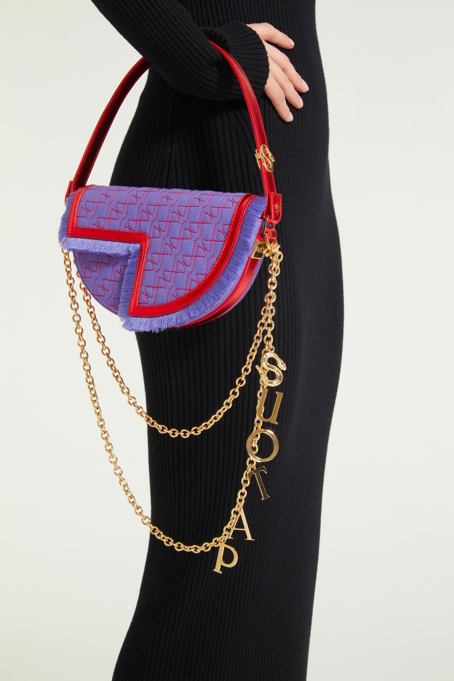 Patou - Le Petit Patou x Sita - Purple Blue Red - A high-octane remix on a Patou favouriteViolet denim-effect recycled organic cotton and red metallic leather handbag. Part of a special collaboration with DJ and designer Sita Abellán. Crafted using premium deadstock leather. Half-circle shape with geometric cut-outs inspired by the JP monogram. Allover JP quilting in red. Gold-tone hardware with Patou-engraved detail at the side. Leather outline with fringed edges. Removable leather strap adorned with Sita's signature snake that allows it to be worn on the shoulder or carried by hand. Might be replaced by a gold-tone brass chain strap (sold separately) adorned with Patou letter charms and Sita's snake symbol; the chain can be used as single or double length and worn on the shoulder, across the body or at the waist to turn Le Petit Patou into a belt bag. Magnetic closure with gold-tone JP detail. Internal compartment. Eco lining.Measures: 20cm (length), 13cm (height), 5cm (depth)