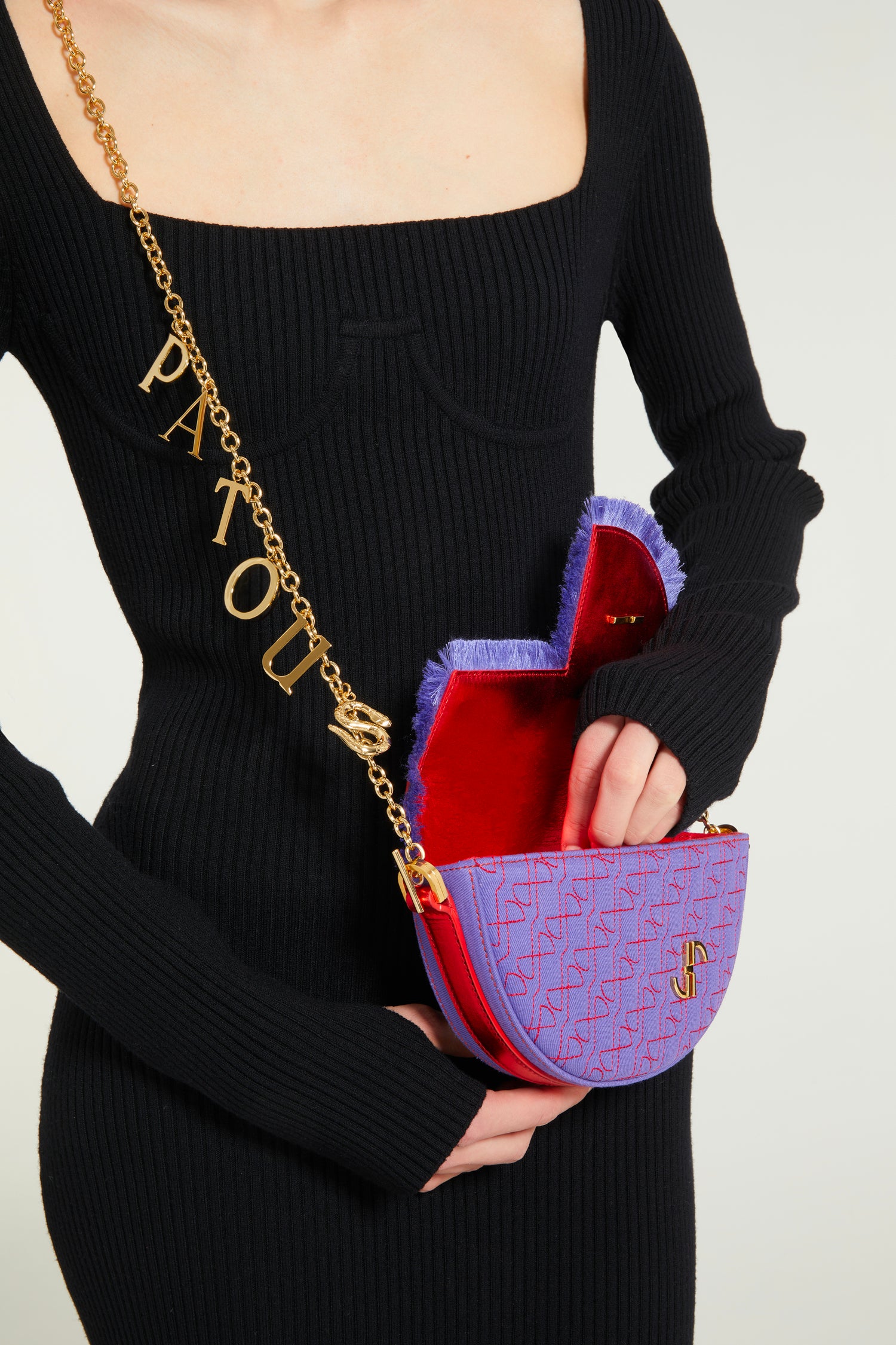 Patou - Le Petit Patou x Sita - Purple Blue Red - A high-octane remix on a Patou favouriteViolet denim-effect recycled organic cotton and red metallic leather handbag. Part of a special collaboration with DJ and designer Sita Abellán. Crafted using premium deadstock leather. Half-circle shape with geometric cut-outs inspired by the JP monogram. Allover JP quilting in red. Gold-tone hardware with Patou-engraved detail at the side. Leather outline with fringed edges. Removable leather strap adorned with Sita's signature snake that allows it to be worn on the shoulder or carried by hand. Might be replaced by a gold-tone brass chain strap (sold separately) adorned with Patou letter charms and Sita's snake symbol; the chain can be used as single or double length and worn on the shoulder, across the body or at the waist to turn Le Petit Patou into a belt bag. Magnetic closure with gold-tone JP detail. Internal compartment. Eco lining.Measures: 20cm (length), 13cm (height), 5cm (depth)