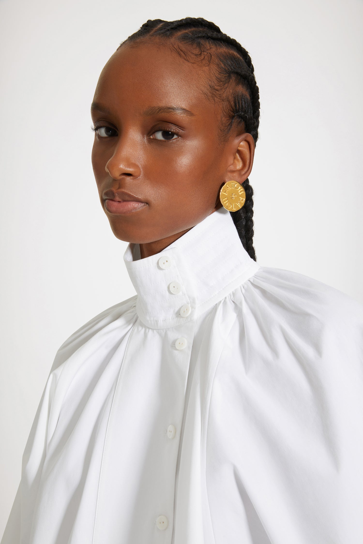 Patou - Blusa a collo alto in cotone bio - White - La blusa da pittore, un capolavoro contemporaneo. Blusa in cotone bio bianco. Silhouette asimmetrica con vestibilità ampia. Collo alto. Chiusura parziale con bottoni sul davanti. Dettaglio di ruche sul retro. Maniche a pipistrello. Polsini abbottonati. Vestibilità ampia (seleziona una taglia in meno per un look aderente).