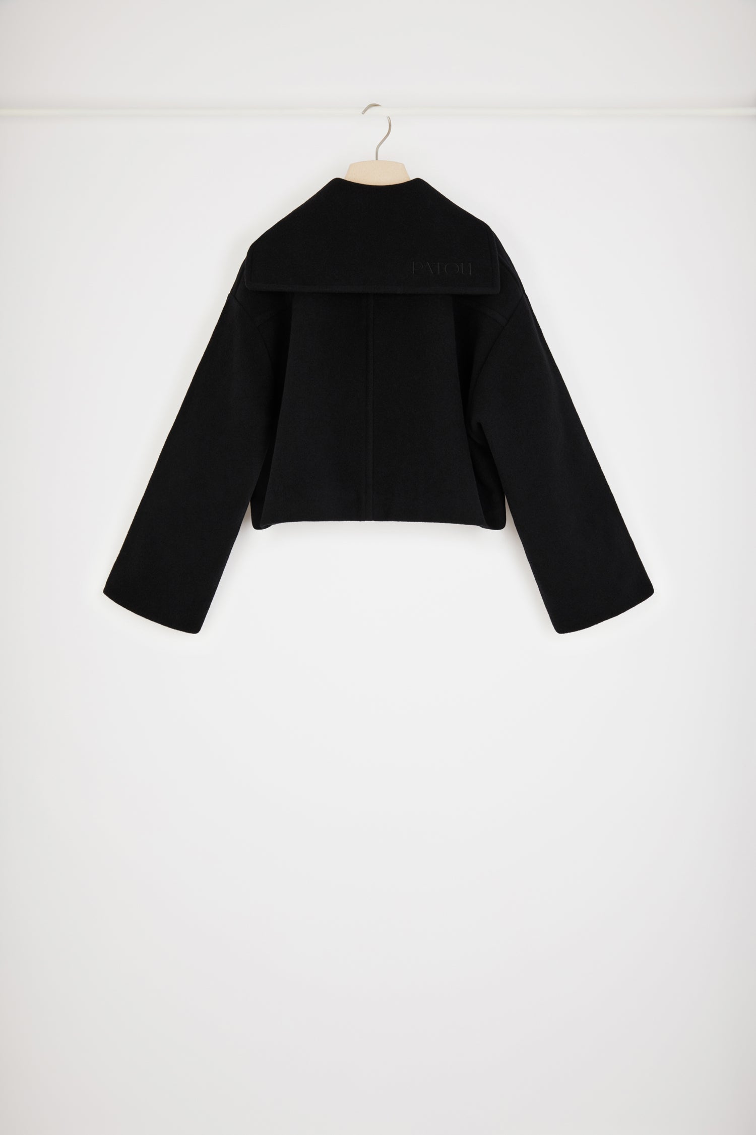 Patou - ダブルフェイスウール クロップコート - Black - シングルブレスト、ダブルフェイス:パトゥの勝利を約束するアウターのルール。ブラックのダブルフェイスウール製コート。丈の短いシルエット。シングルブレストデザイン、フロントでオフセンターボタン留め、トップにボタンループ。パトゥ刻印入りゴールドトーンボタン。セータースタイルのフラップカラー、バックにパトゥロゴ刺繍。オーバーサイズ パッチポケット。ルーズフィット(フィット感をお求めの場合はワンサイズ下をお選びください)。