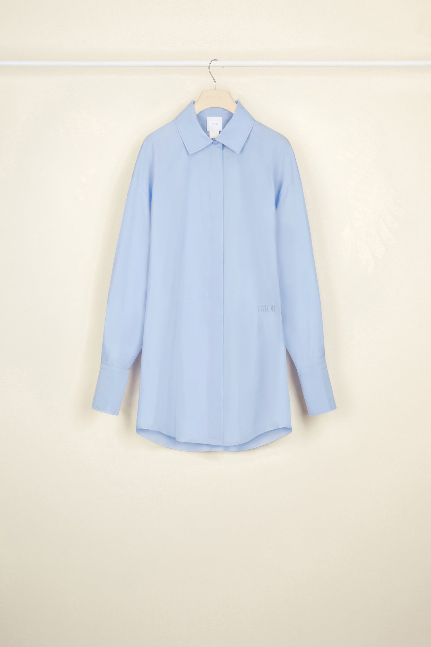 Patou - Mini shirt dress in organic cotton - Aurora - Layered or on its own, a new shape to make your own.Aurora light blue organic cotton poplin shirt dress. Short length. Loose silhouette. Shirt collar. Concealed button fastening with JP engraved buttons. Patou logo embroidered at the front. Signature curved seam at the back. Buttoned cuffs.